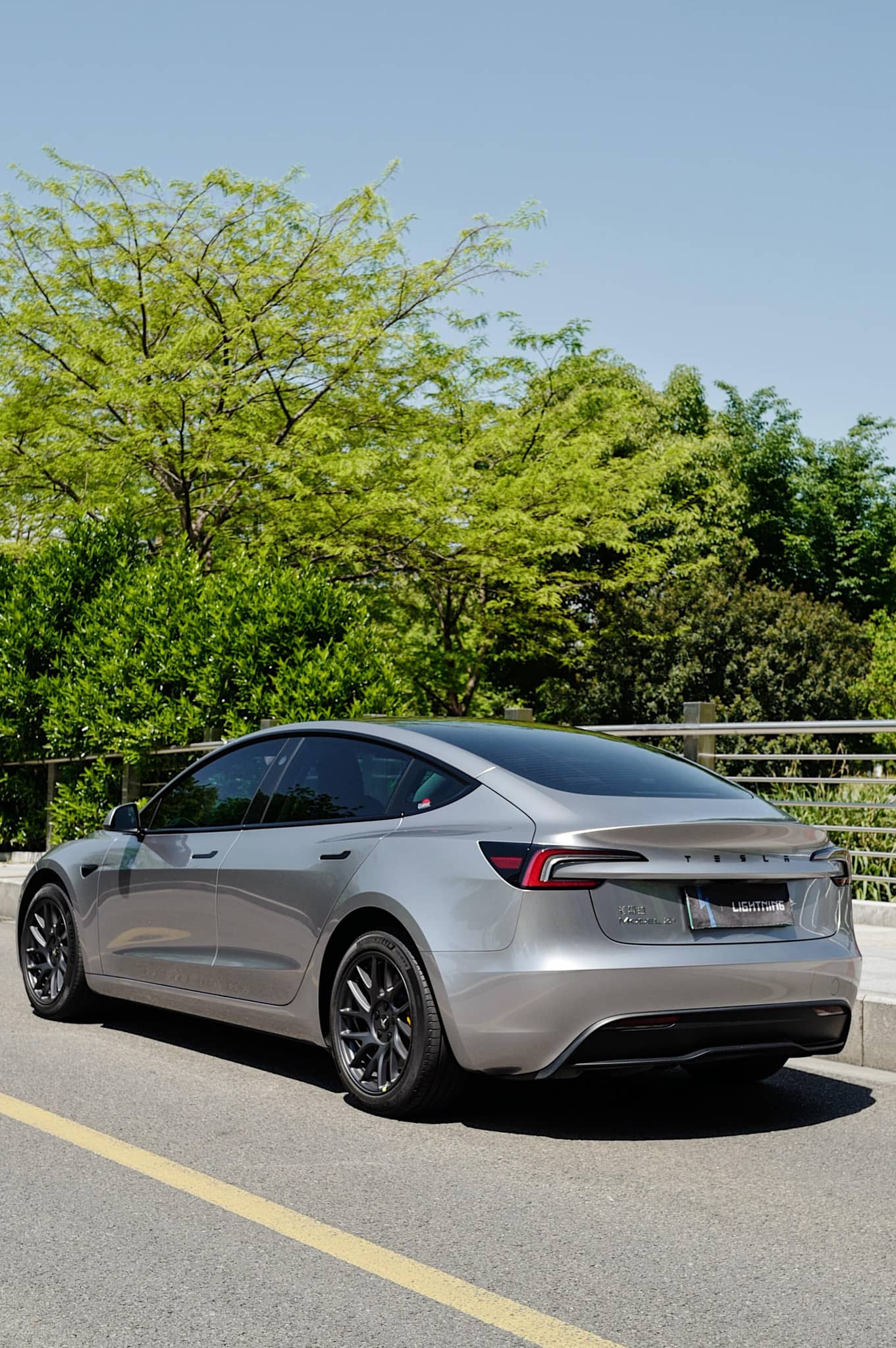 Silver Tesla Model 3 parked on road featuring a Pre-cut Tesla Wrap Kit by WrapBug