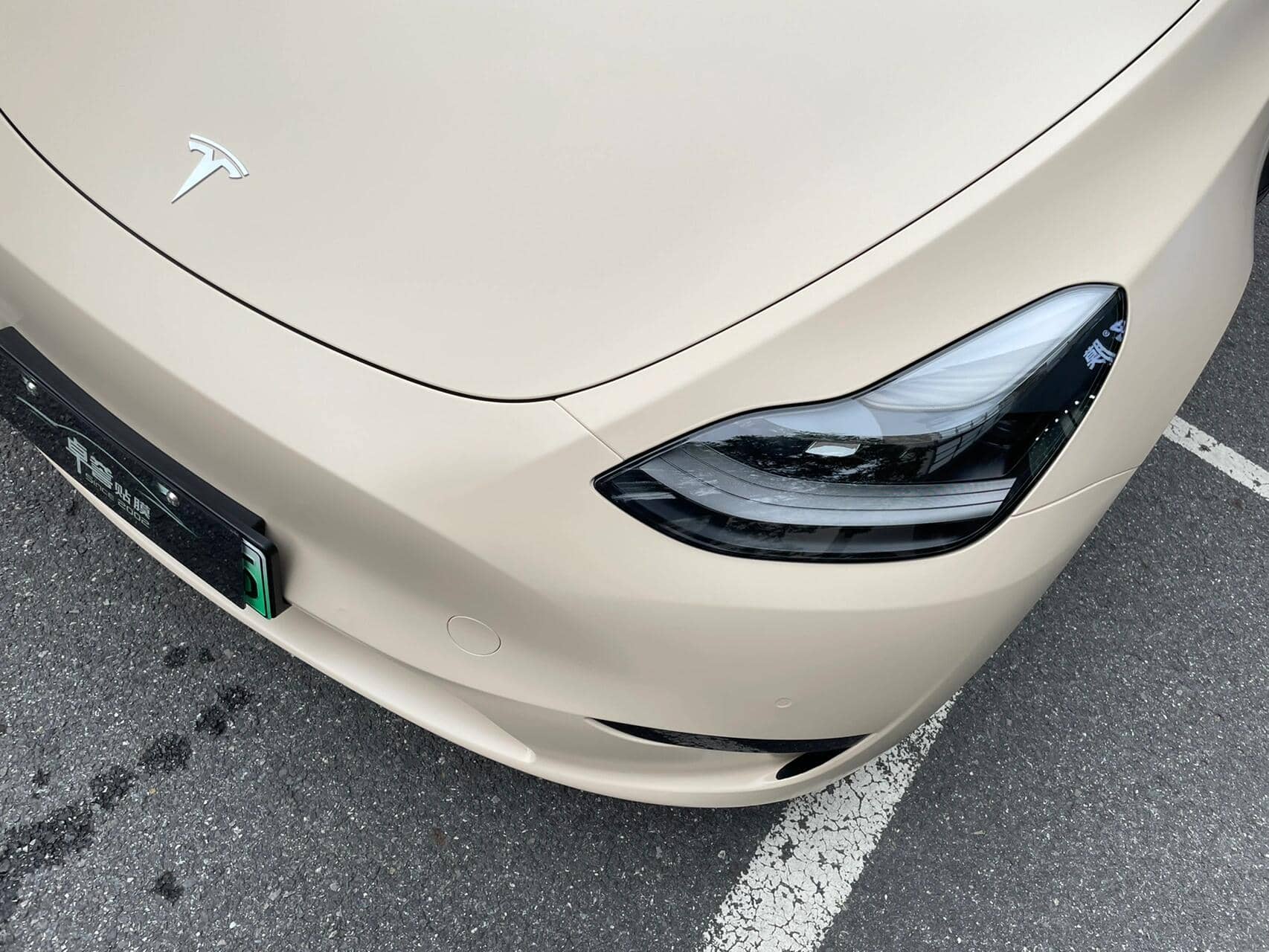 Front corner of Tesla car with matte MATTE SPACE GRAY tesla wrap showing headlight and hood details