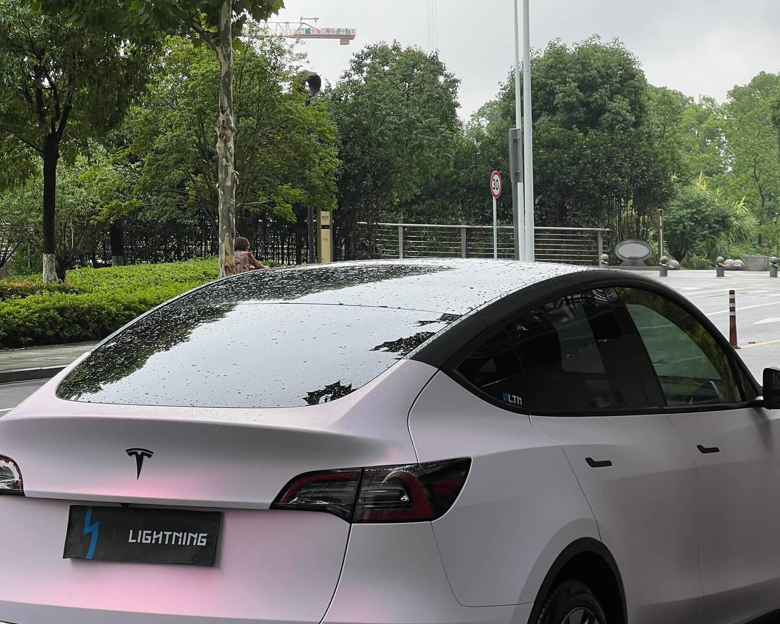 WrapBug matte pink Tesla Model Y parked outdoors with rain droplets on roof and tinted windows
