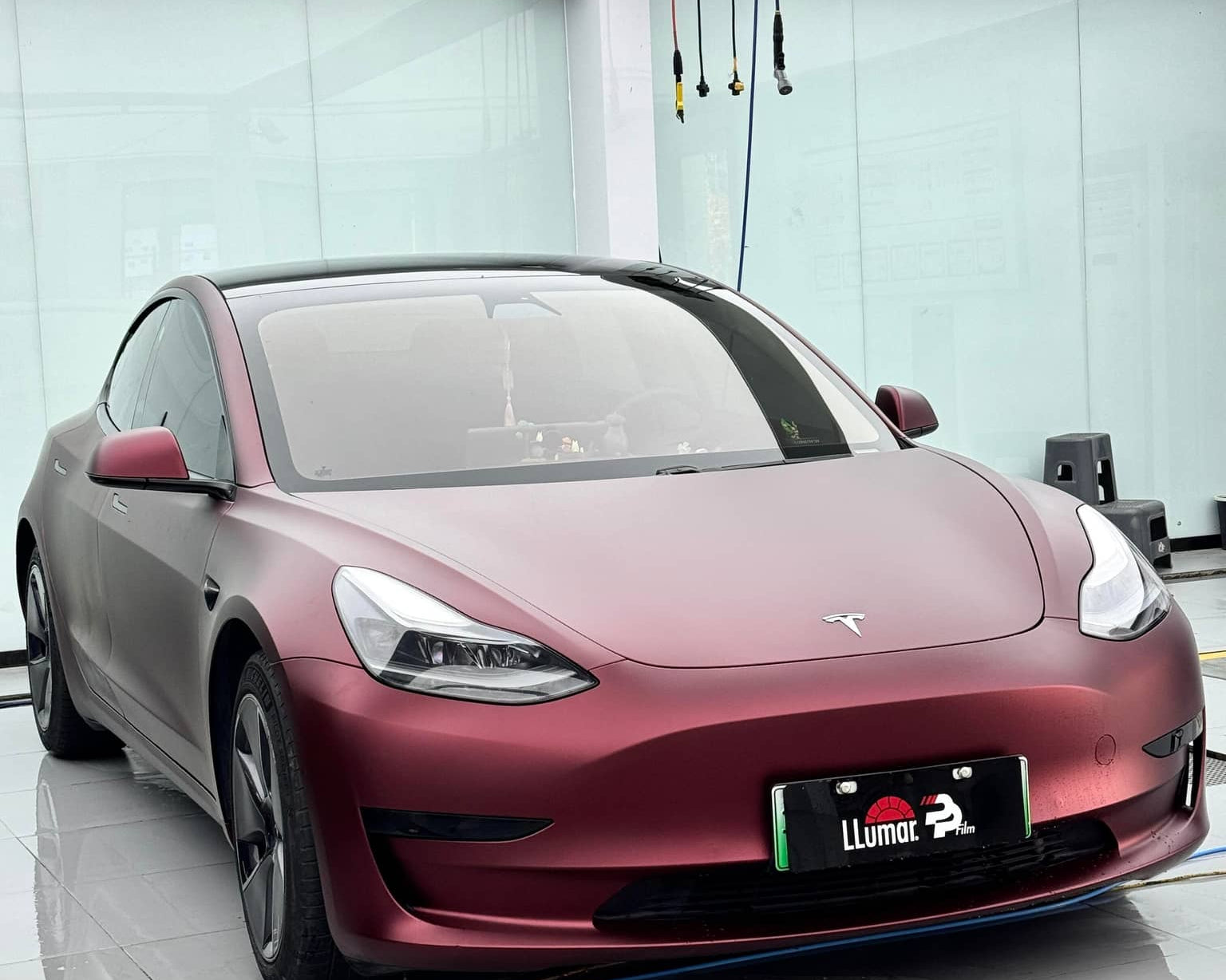 Matte burgundy Tesla Model 3 with custom car wrap by WrapBug in a clean studio setting