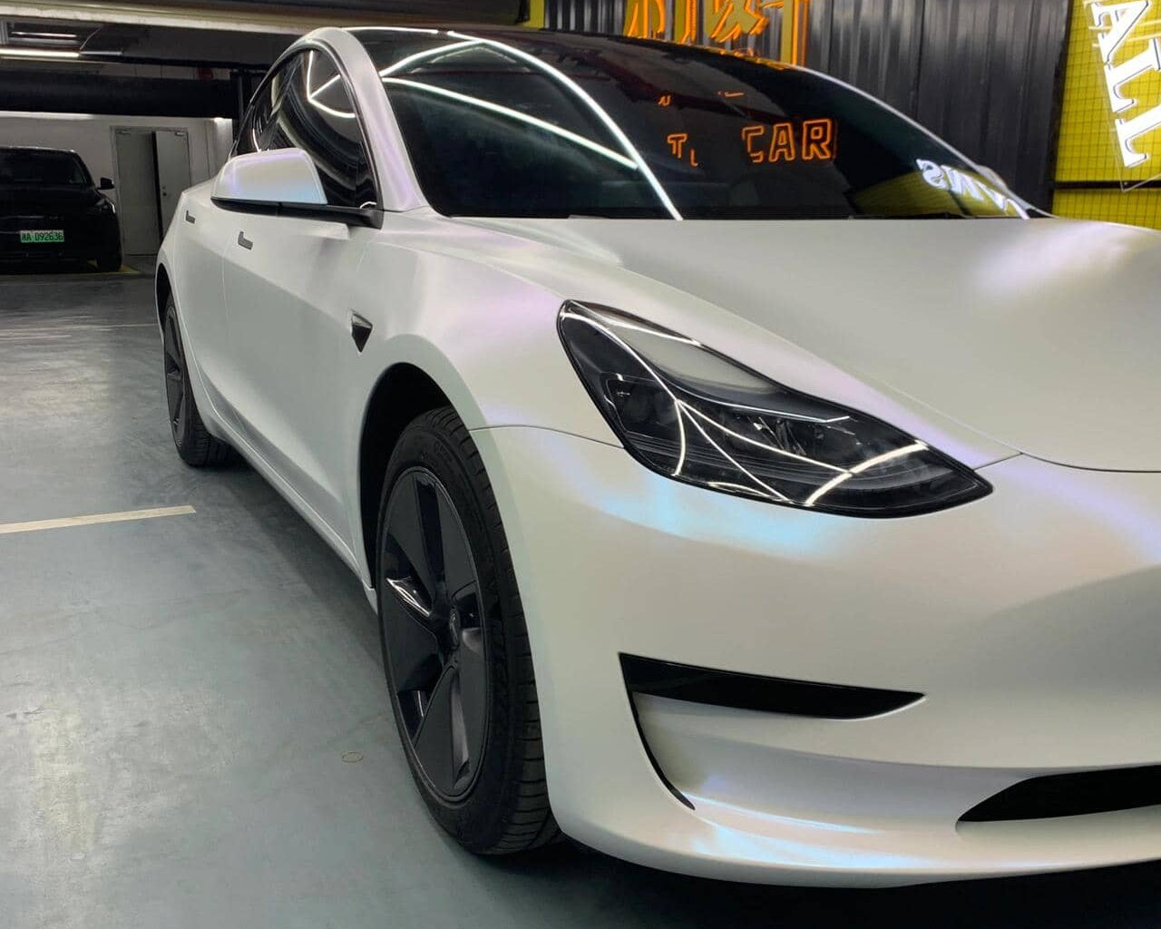 Tesla Model 3 featuring a matte white tesla wrap by WrapBug in a showroom setting