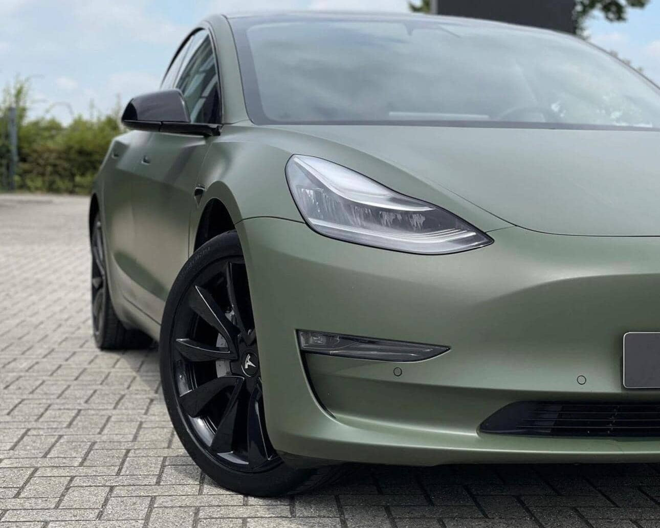 Tesla Model 3 electric car with matte green WrapBug vinyl wrap and black alloy wheels