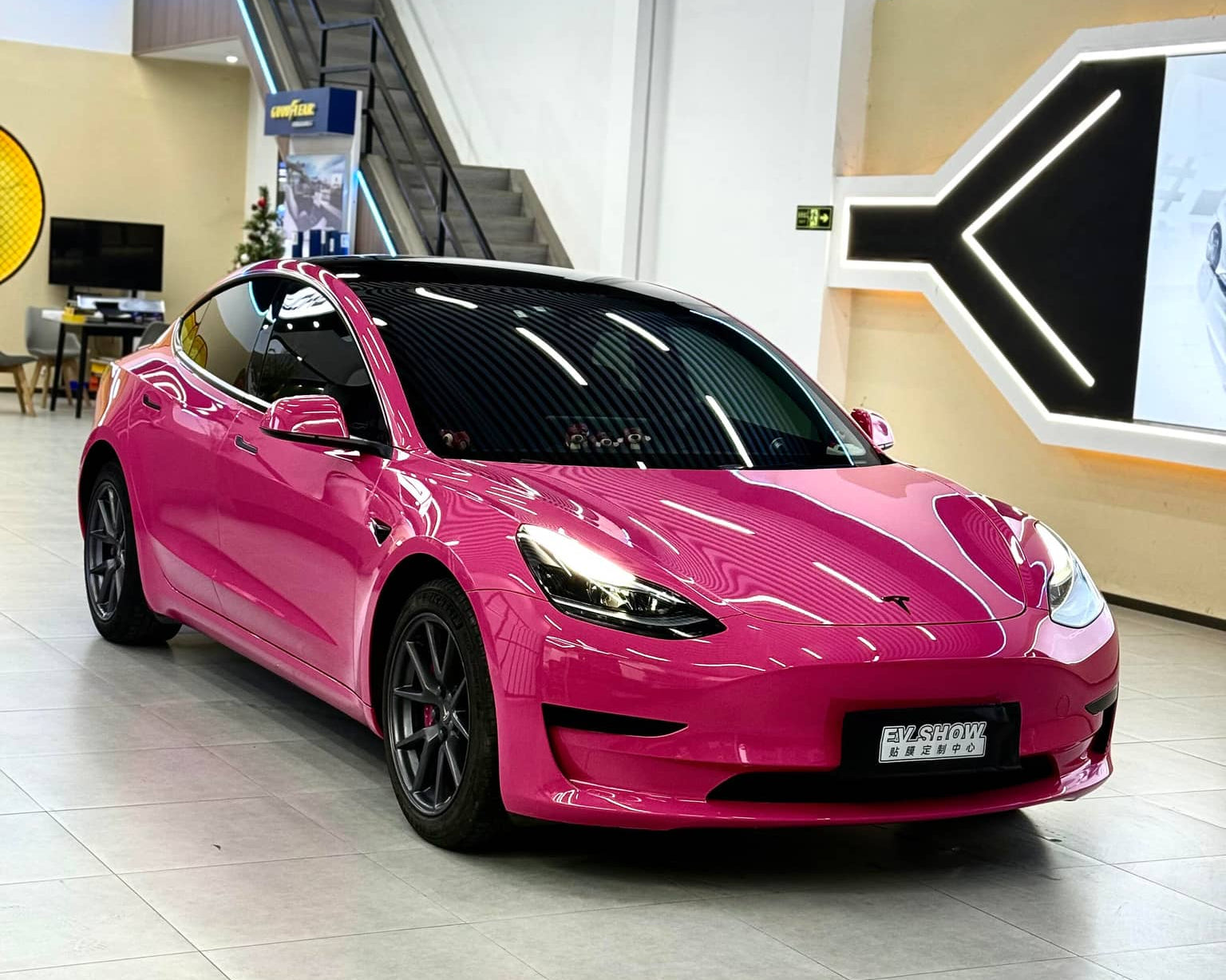 Pink Tesla Model 3 wrapped with WrapBug Pre-cut Tesla Vinyl Wrap in a showroom