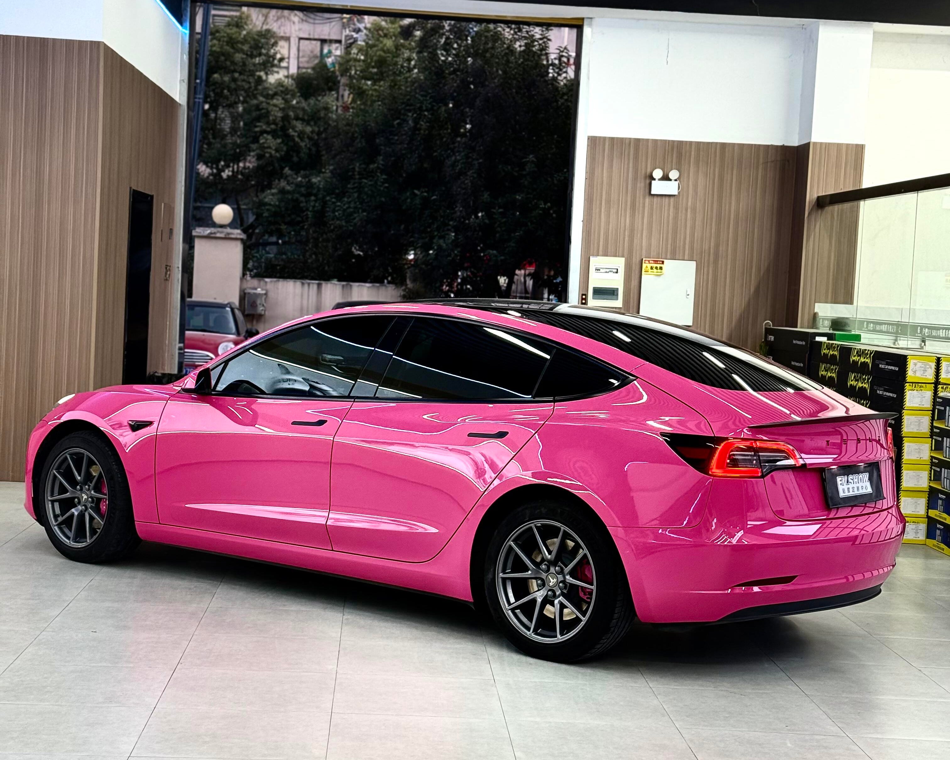 Tesla car wrapped in bright pink Pre-cut Tesla Vinyl Wrap parked indoors