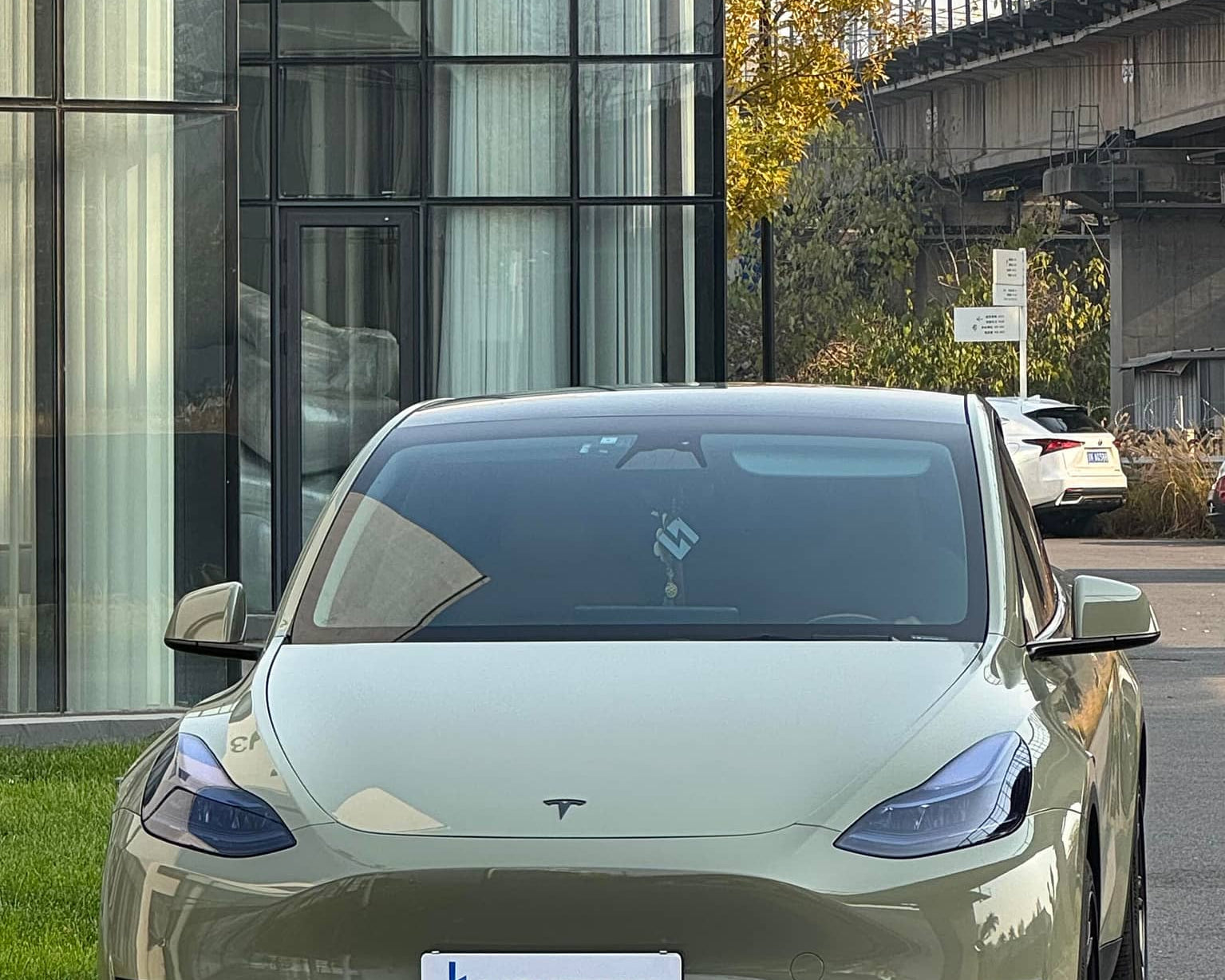 Tesla Model 3 with olive green pre-cut Tesla vinyl wrap kit parked in urban setting