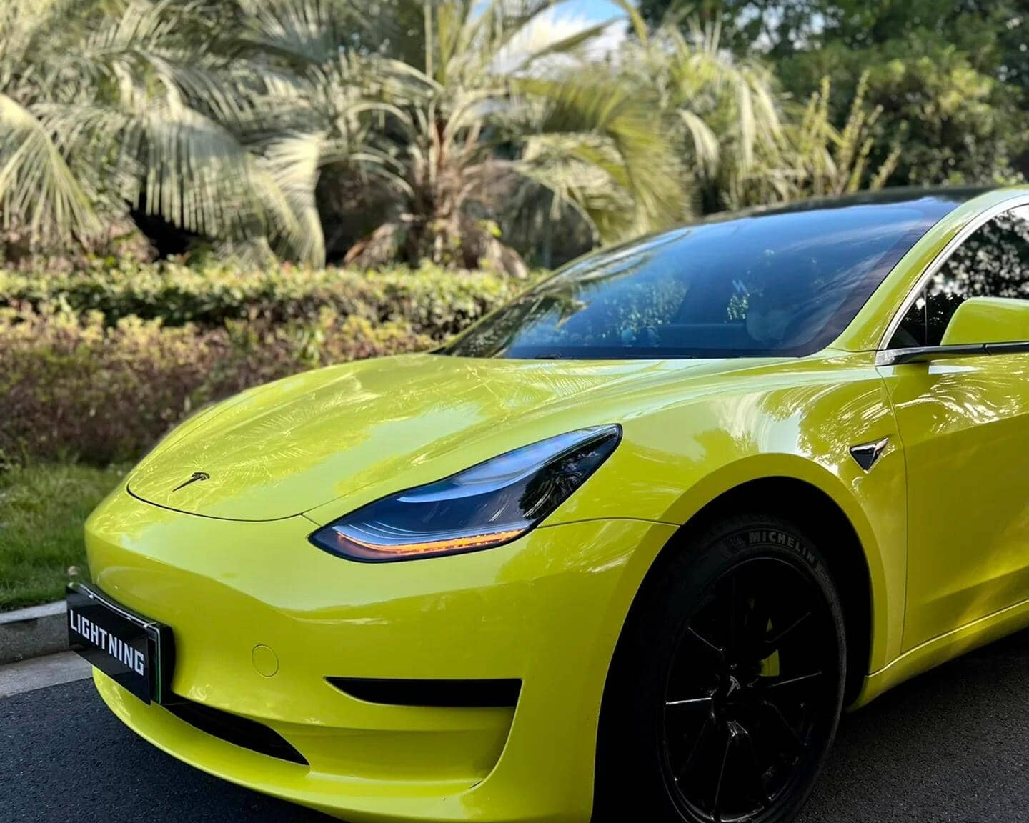 Bright yellow Tesla Model 3 featuring a Pre-cut Tesla Vinyl Wrap Kit on a sunny day