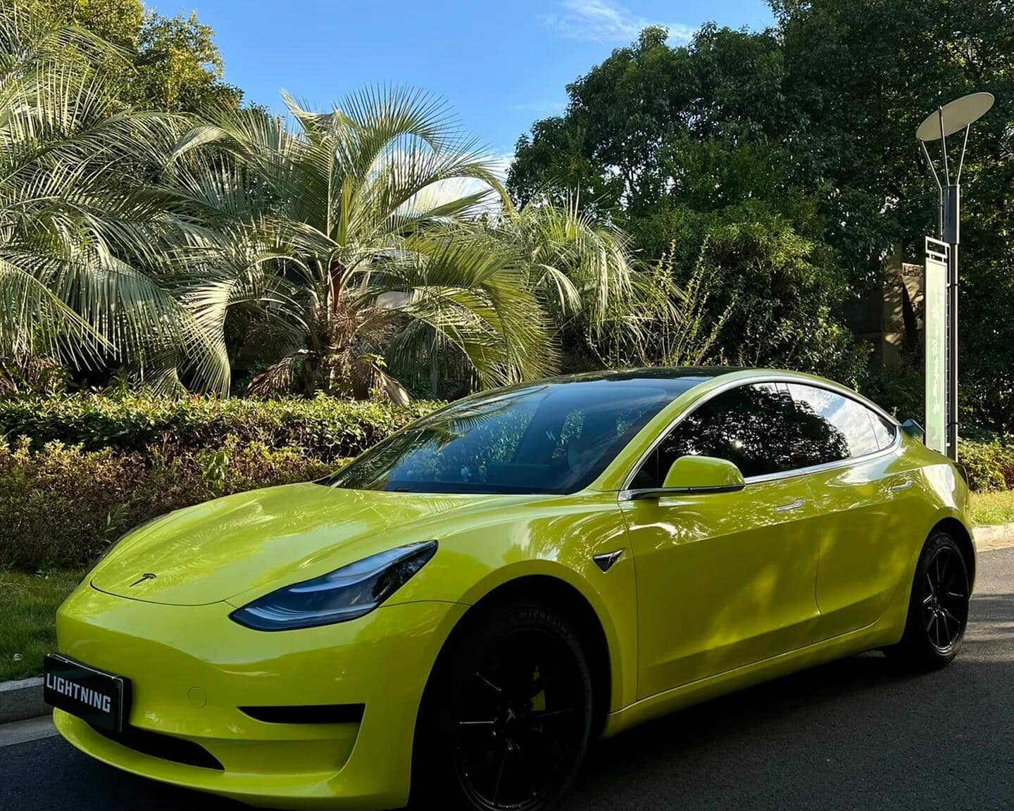 Yellow Tesla car wrapped using Pre-cut Tesla Vinyl Wrap Kit parked outdoors near palm trees