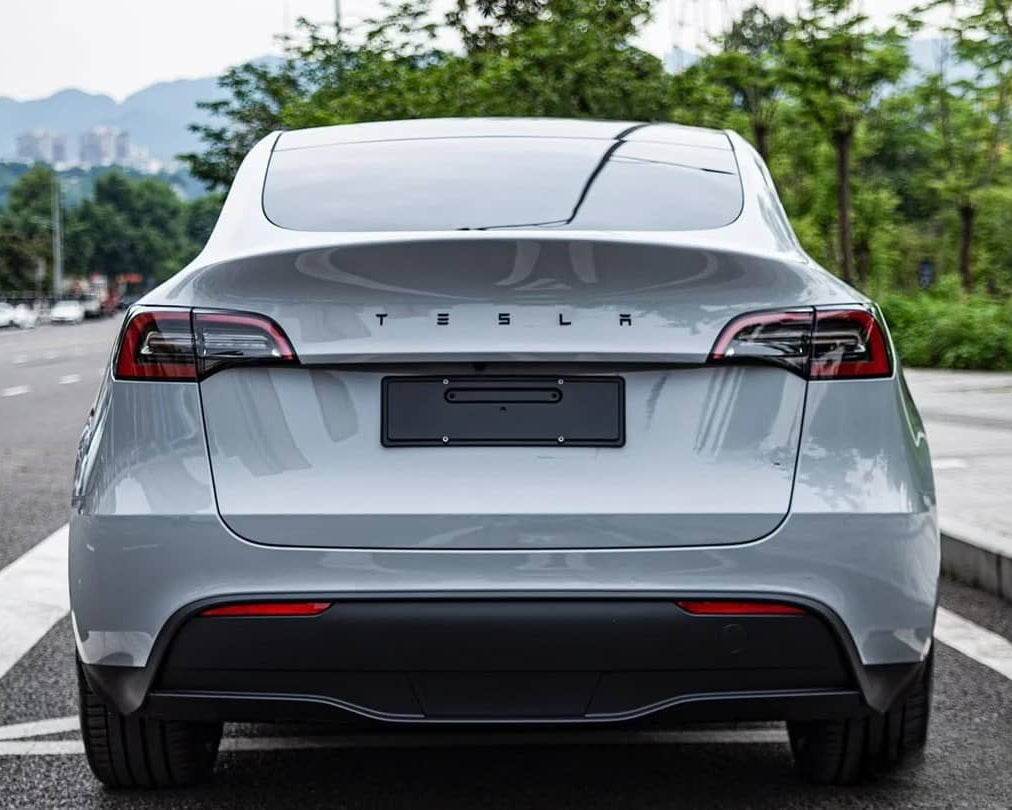 Rear view of white Tesla Model Y featuring a Pre-cut Tesla Wrap Kit by WrapBug on a city street