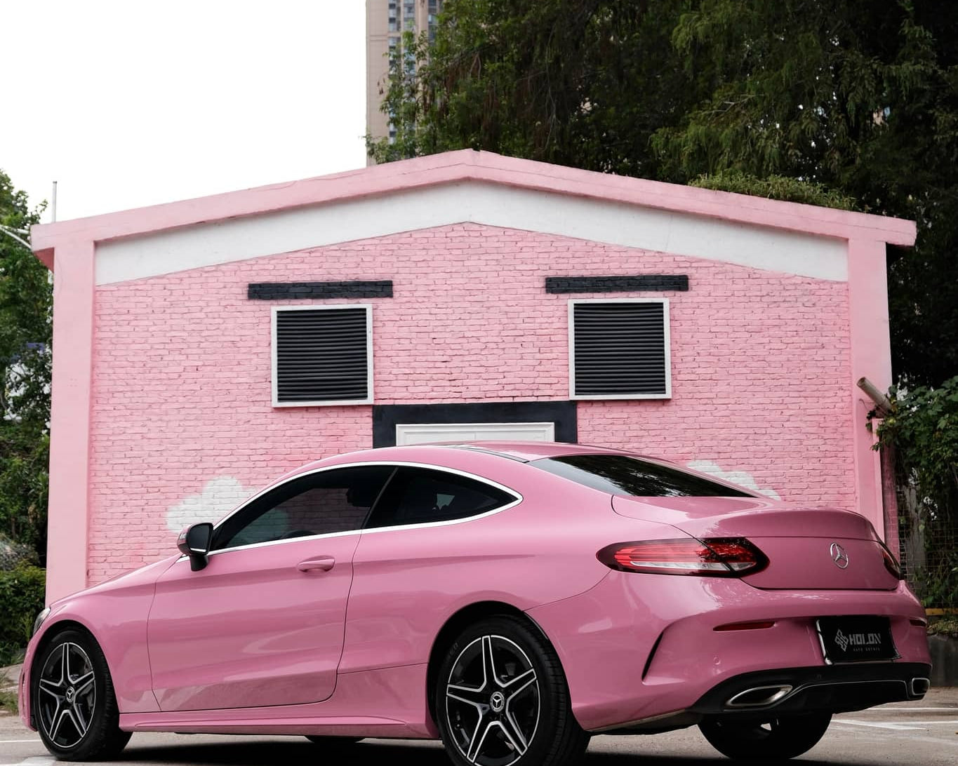 Pink luxury car wrapped with Pre-cut Tesla Wrap Kit parked in front of a pink building
