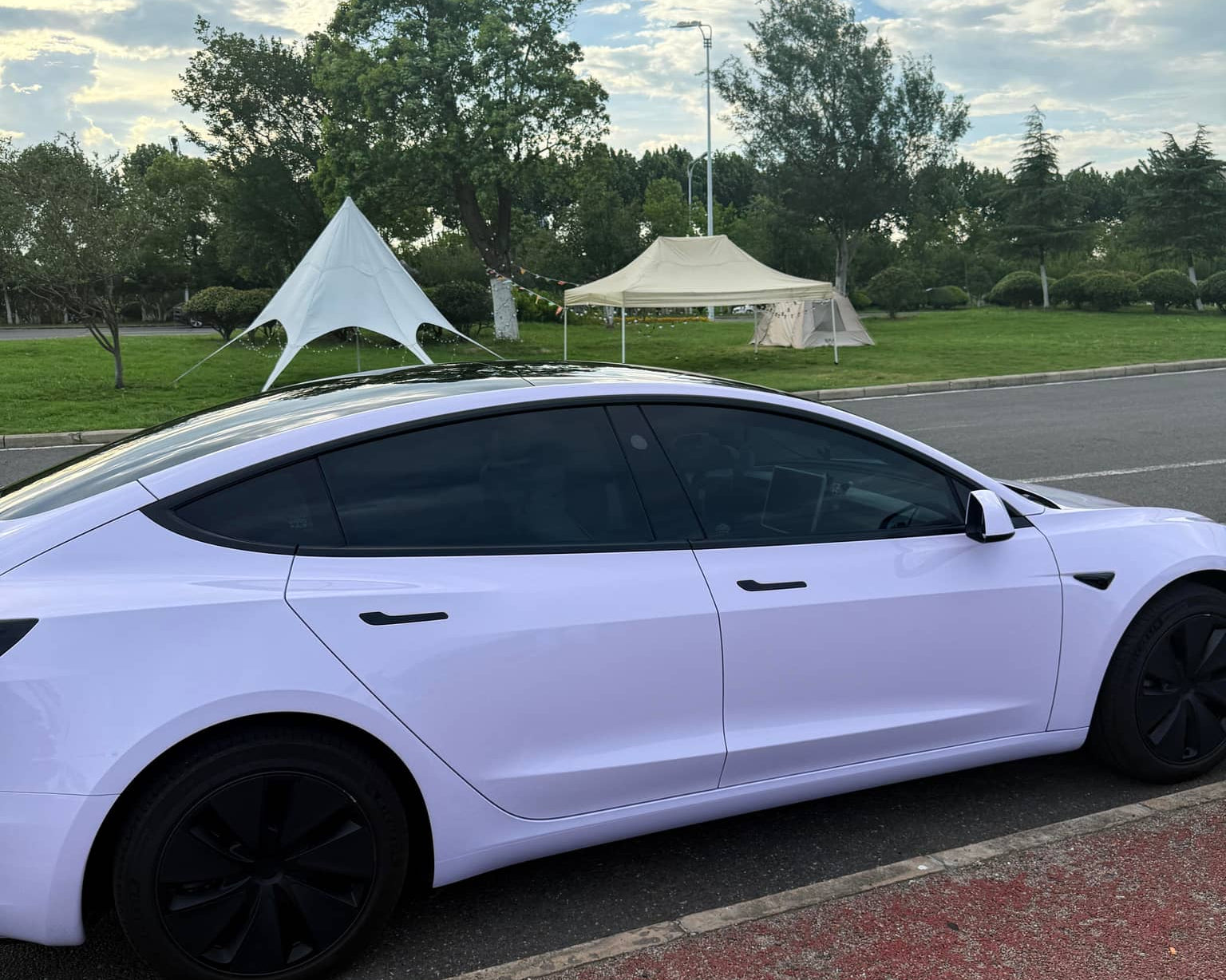 White Tesla Model 3 with Pre-cut Tesla Wrap Kit applied parked beside a road in daylight
