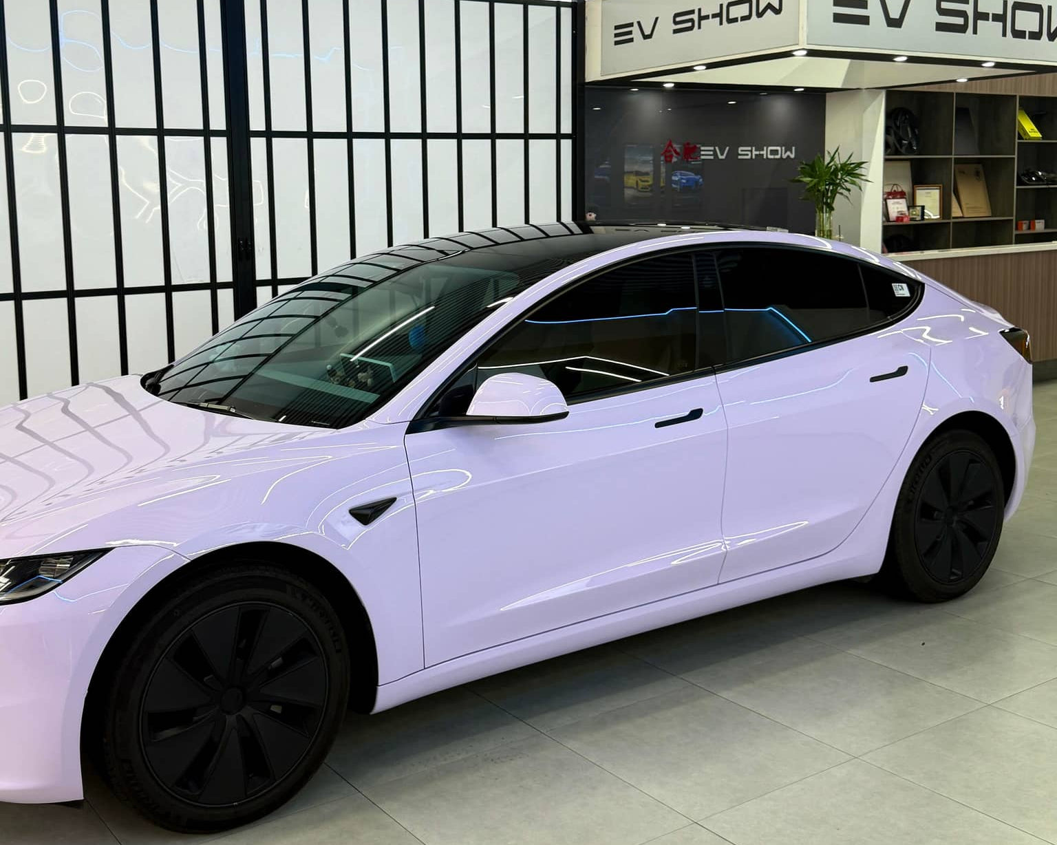 White Tesla Model 3 wrapped with a Pre-cut Tesla Wrap Kit displayed in modern EV showroom