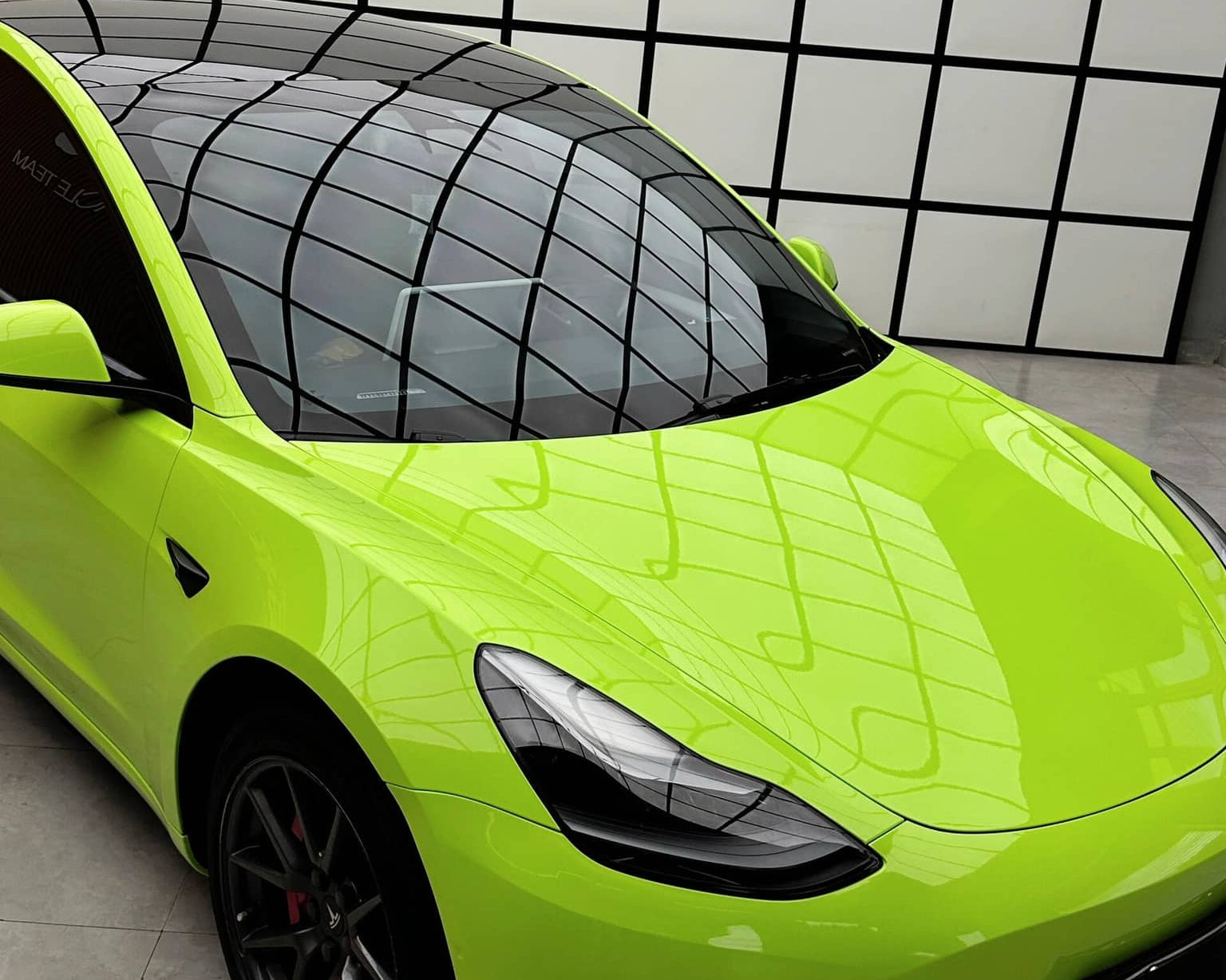 Bright green Tesla with glossy finish using Pre-cut Tesla Wrap Kit by WrapBug in modern showroom