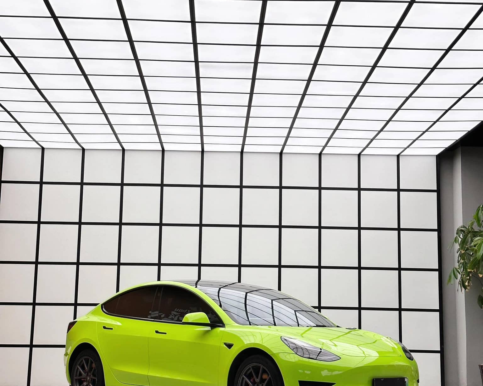 Bright lime green Tesla Model 3 with Pre-cut Tesla Wrap Kit installed in a modern showroom