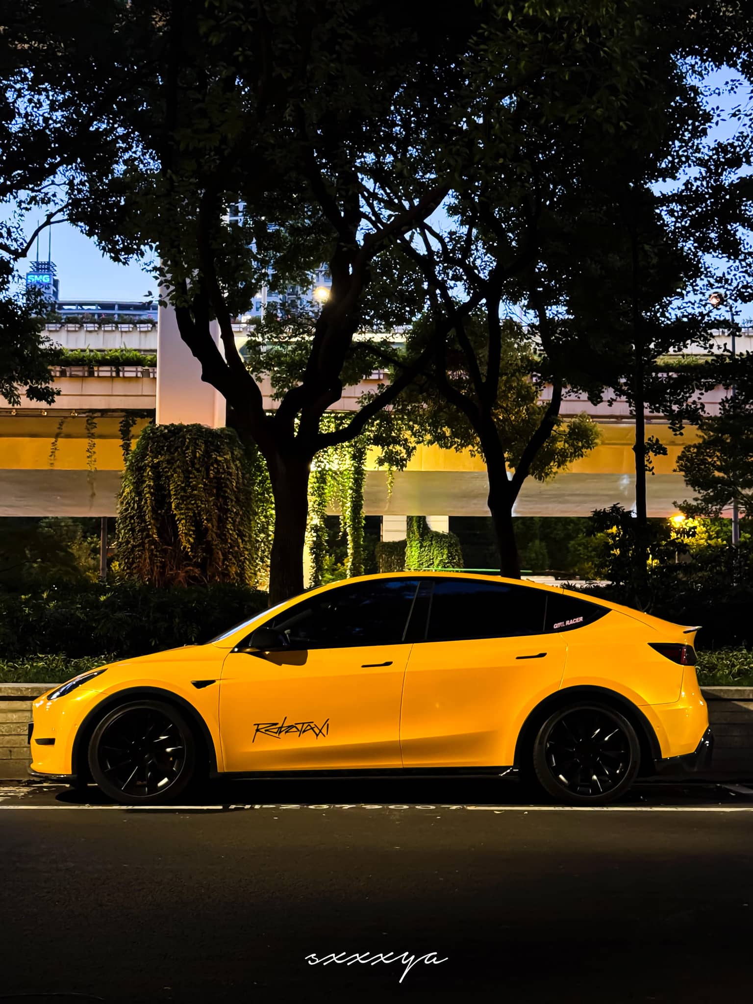 Yellow Tesla Model Y wrapped using Pre-cut Tesla Wrap Kit by WrapBug parked at night under trees