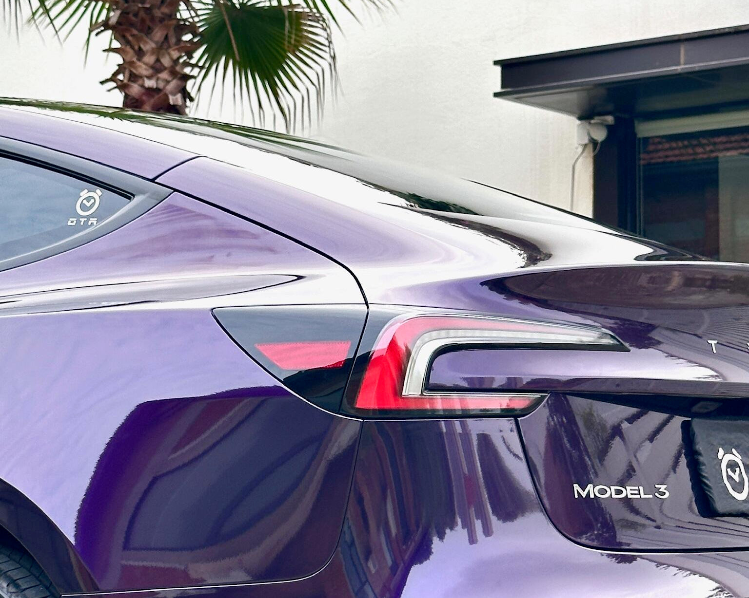 Glossy purple Tesla Model Y rear with Pre-cut Tesla Wrap Kit by WrapBug applied under palm trees