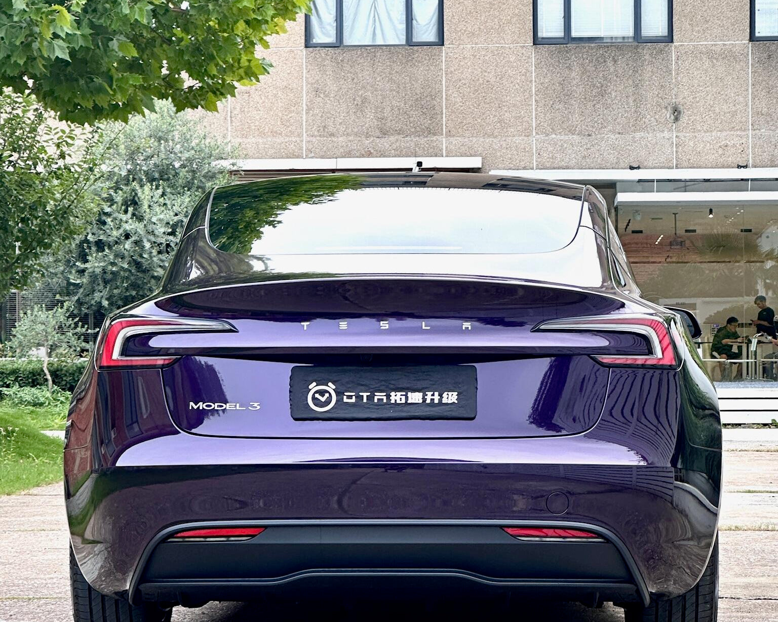 Rear view of a Tesla Model 3 wrapped in a glossy dark purple color using a Pre-cut Tesla Wrap Kit by WrapBug