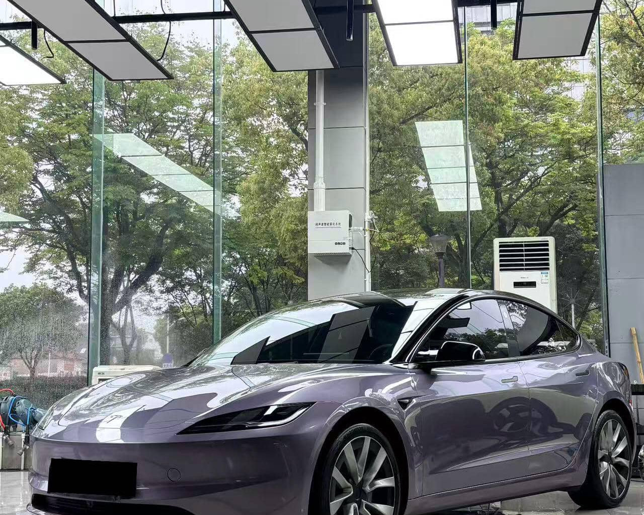 Sleek gray Tesla Model 3 wrapped with Pre-cut Tesla Vinyl Wrap Kit parked inside modern showroom