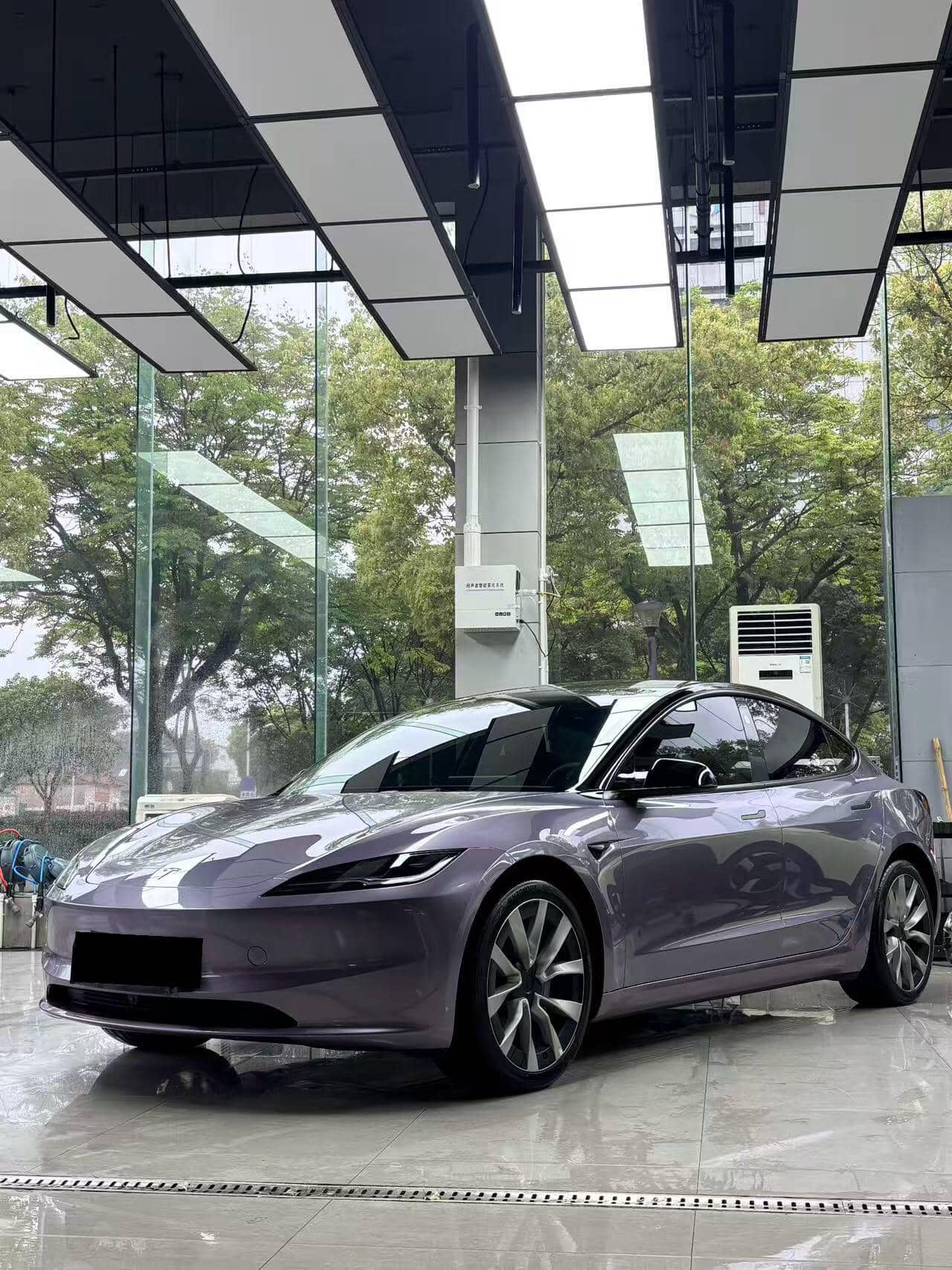 Sleek gray Tesla Model 3 wrapped with Pre-cut Tesla Vinyl Wrap Kit parked inside modern showroom