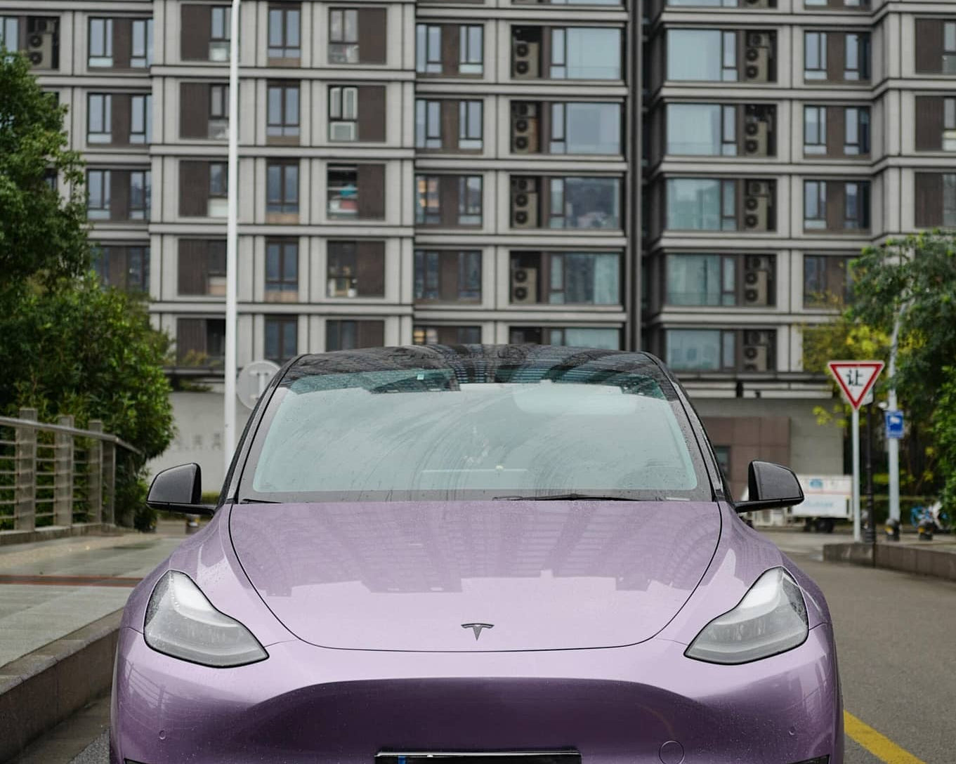 Purple Tesla Model 3 covered with Pre-cut Tesla Wrap Kit parked on urban street with buildings