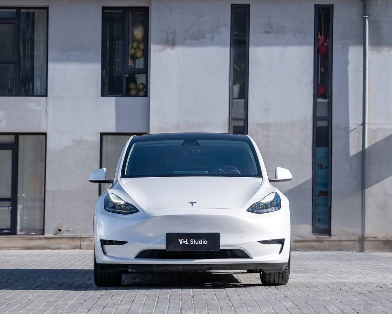 White Tesla Model Y parked in front of building featuring Pre-cut Tesla Wrap Kit by WrapBug