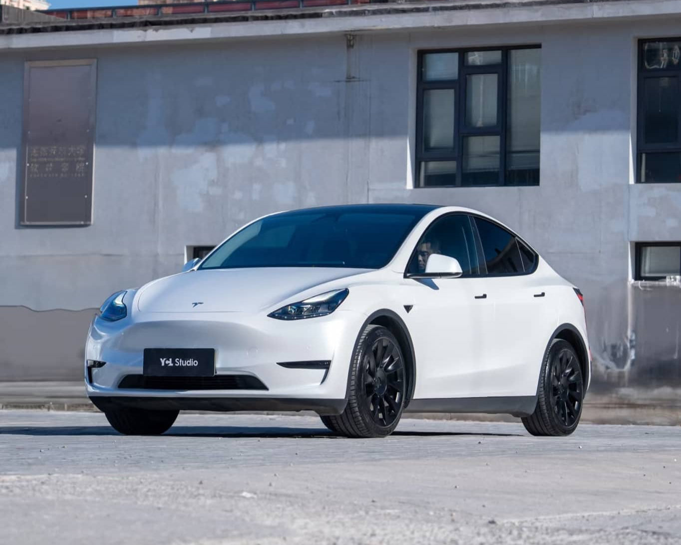 White Tesla Model Y with black wheels parked in urban area featuring Pre-cut Tesla Wrap Kit by WrapBug