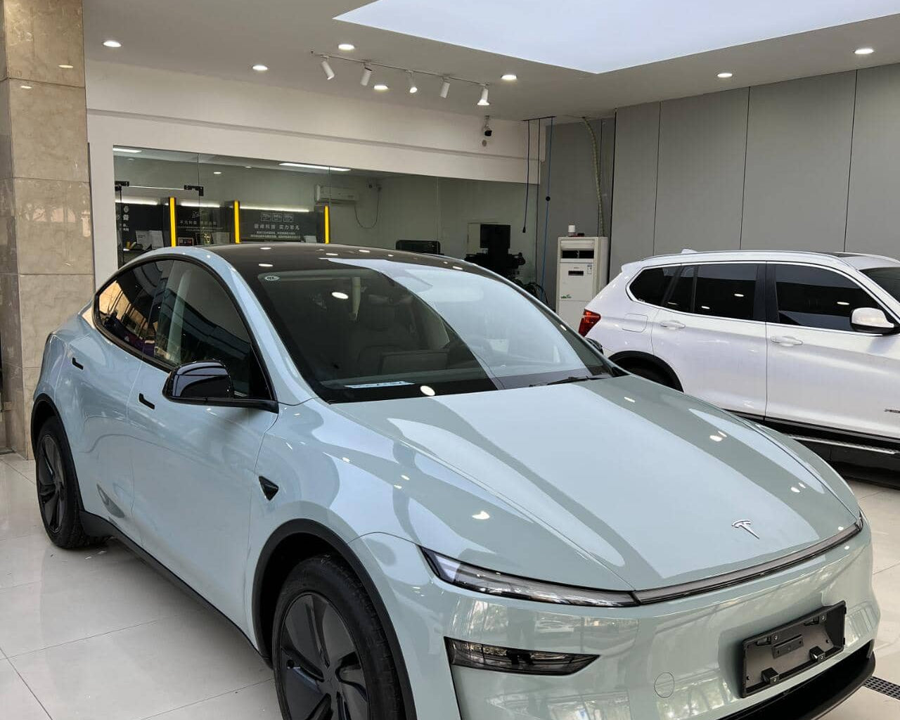 Light blue Tesla SUV with tesla color PPF protective film in a modern showroom