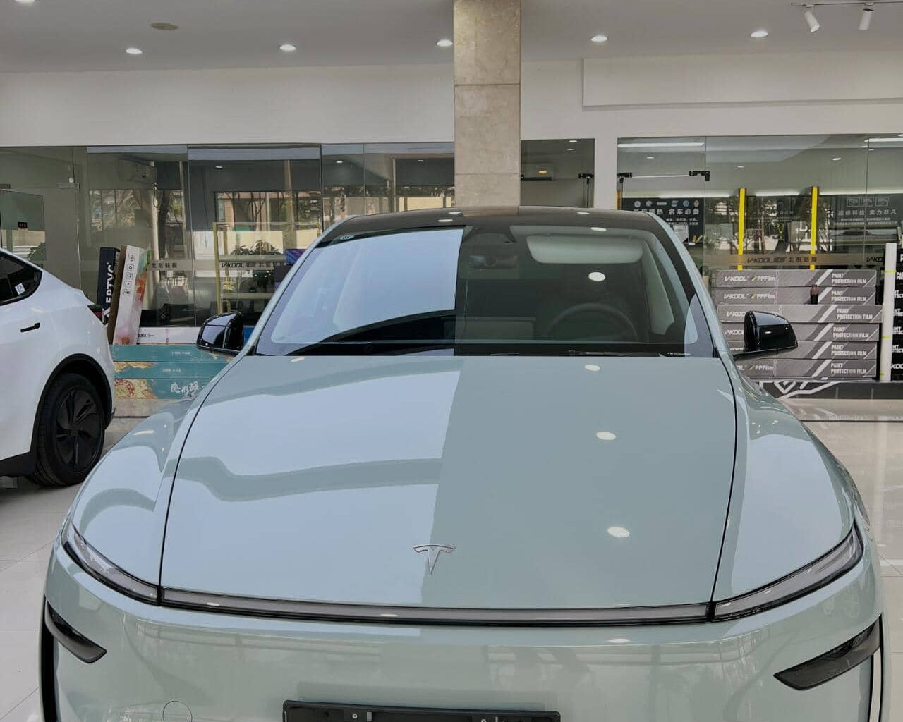Front view of a Tesla car showcasing a clear tesla color PPF coating in a modern showroom