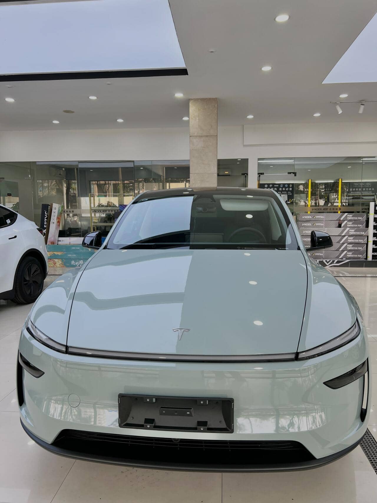 Front view of a Tesla car showcasing a clear tesla color PPF coating in a modern showroom