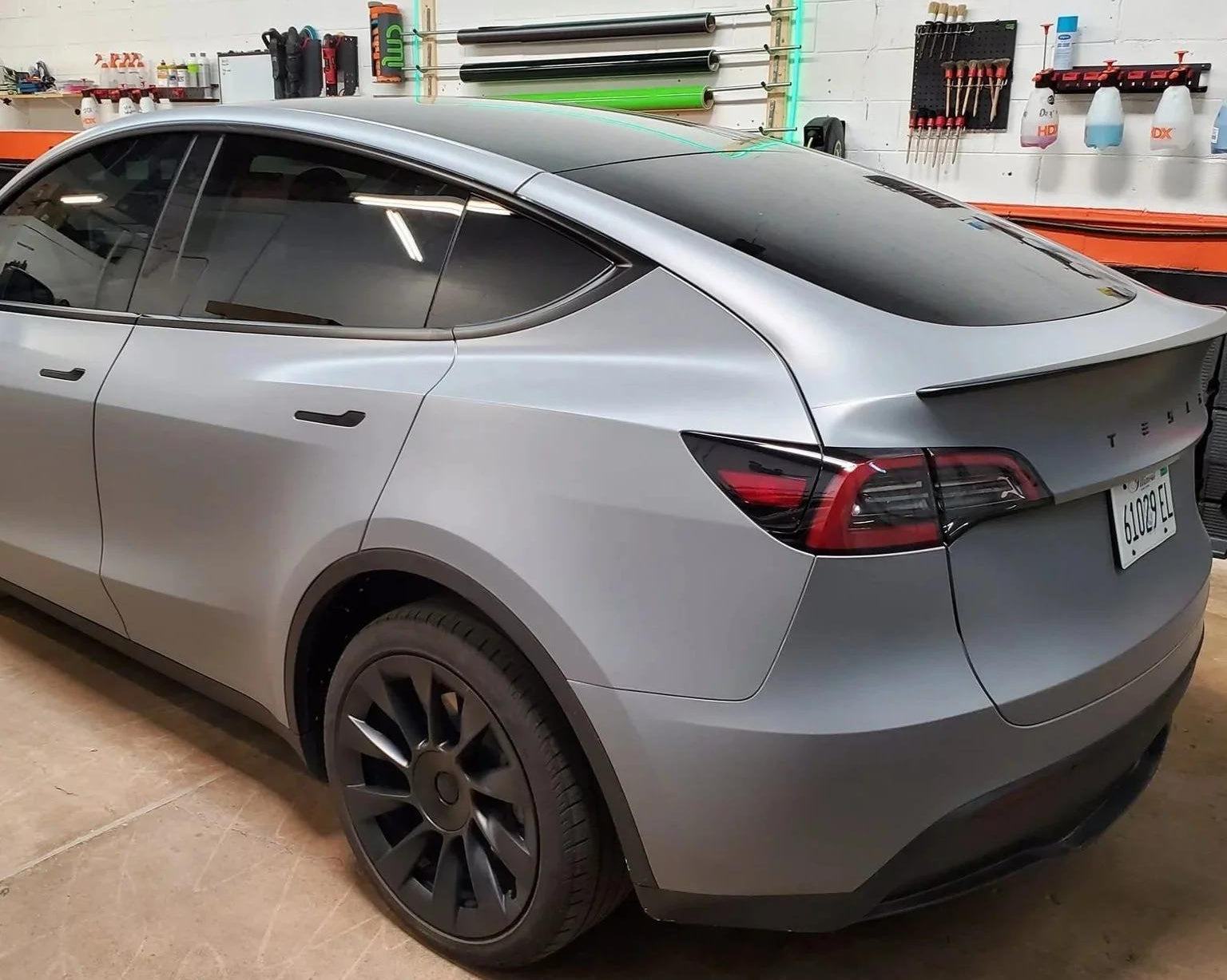 Matte gray tesla model 3 wrap installed on a Tesla Model 3 with tinted windows in a garage