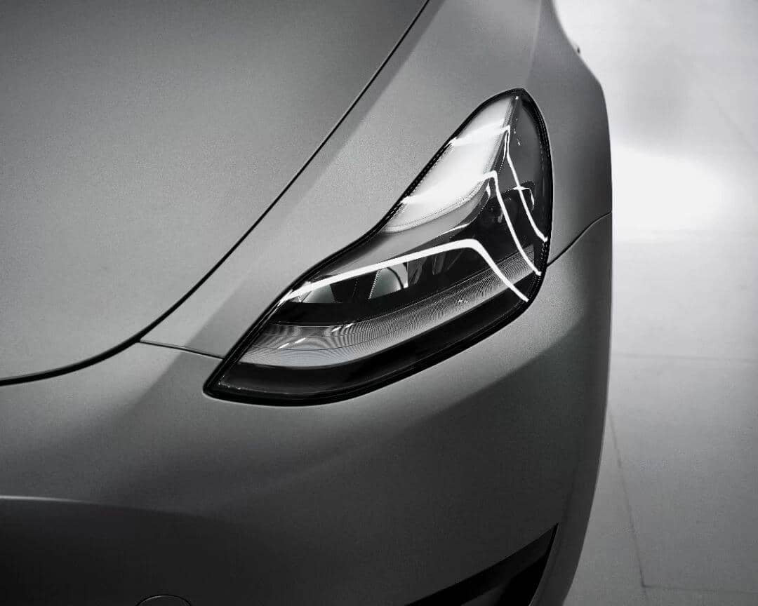Close-up of a sleek gray car headlight with matte finish wrap by WrapBug