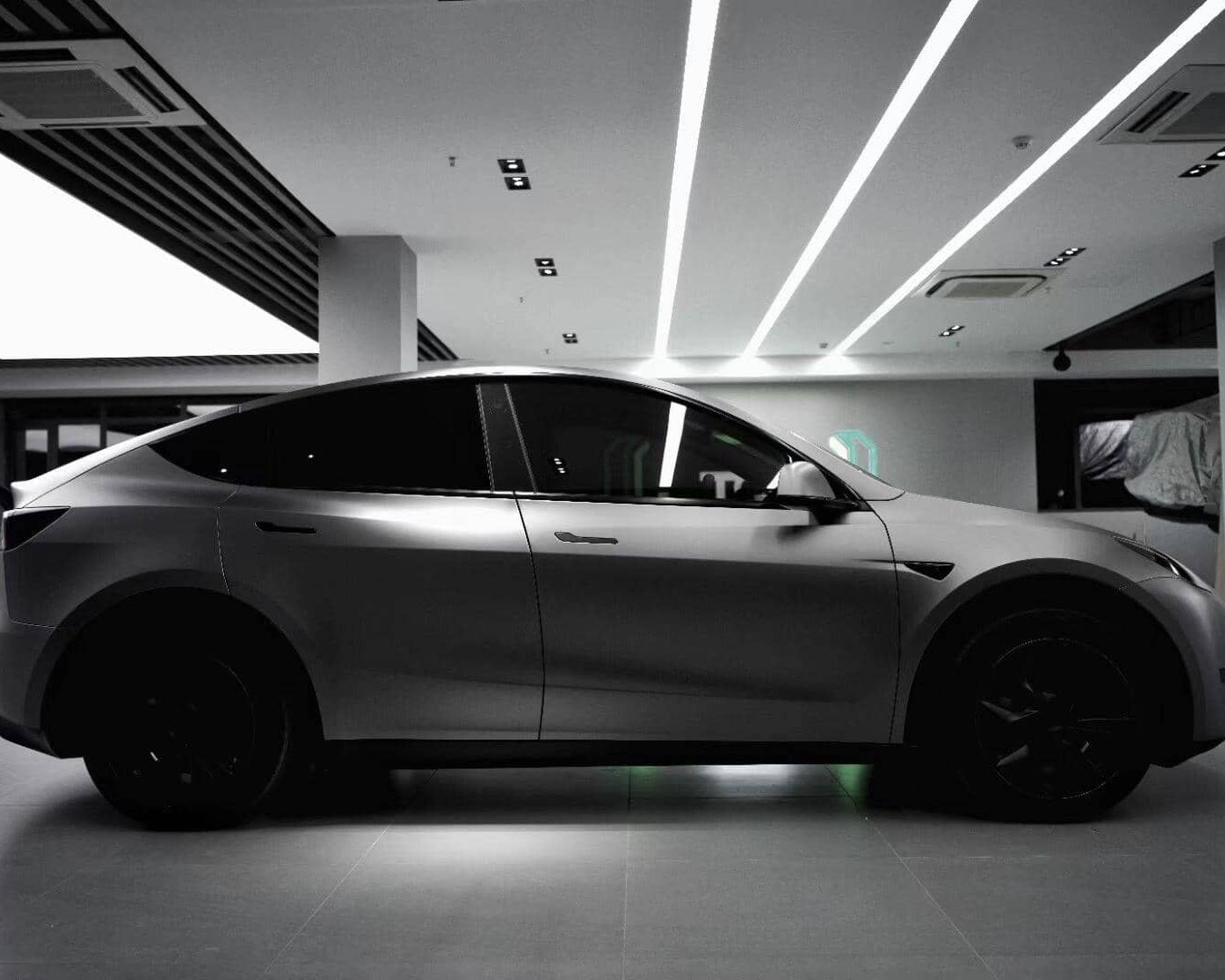Matte black Tesla Model Y electric SUV parked indoors with tinted windows and black wheels