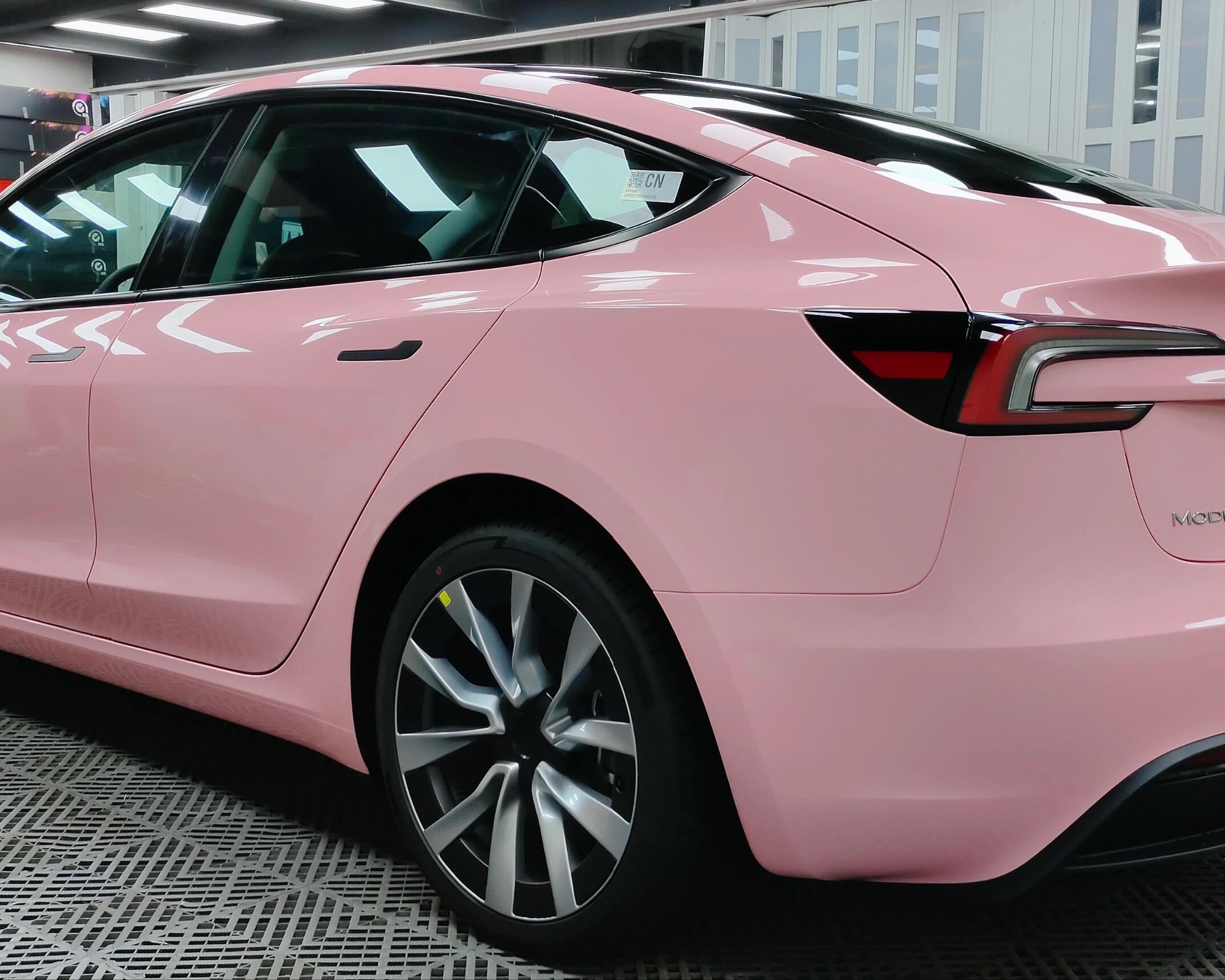 Pink Tesla Model 3 wrapped using Pre-cut Tesla Vinyl Wrap Kit by WrapBug in a professional garage