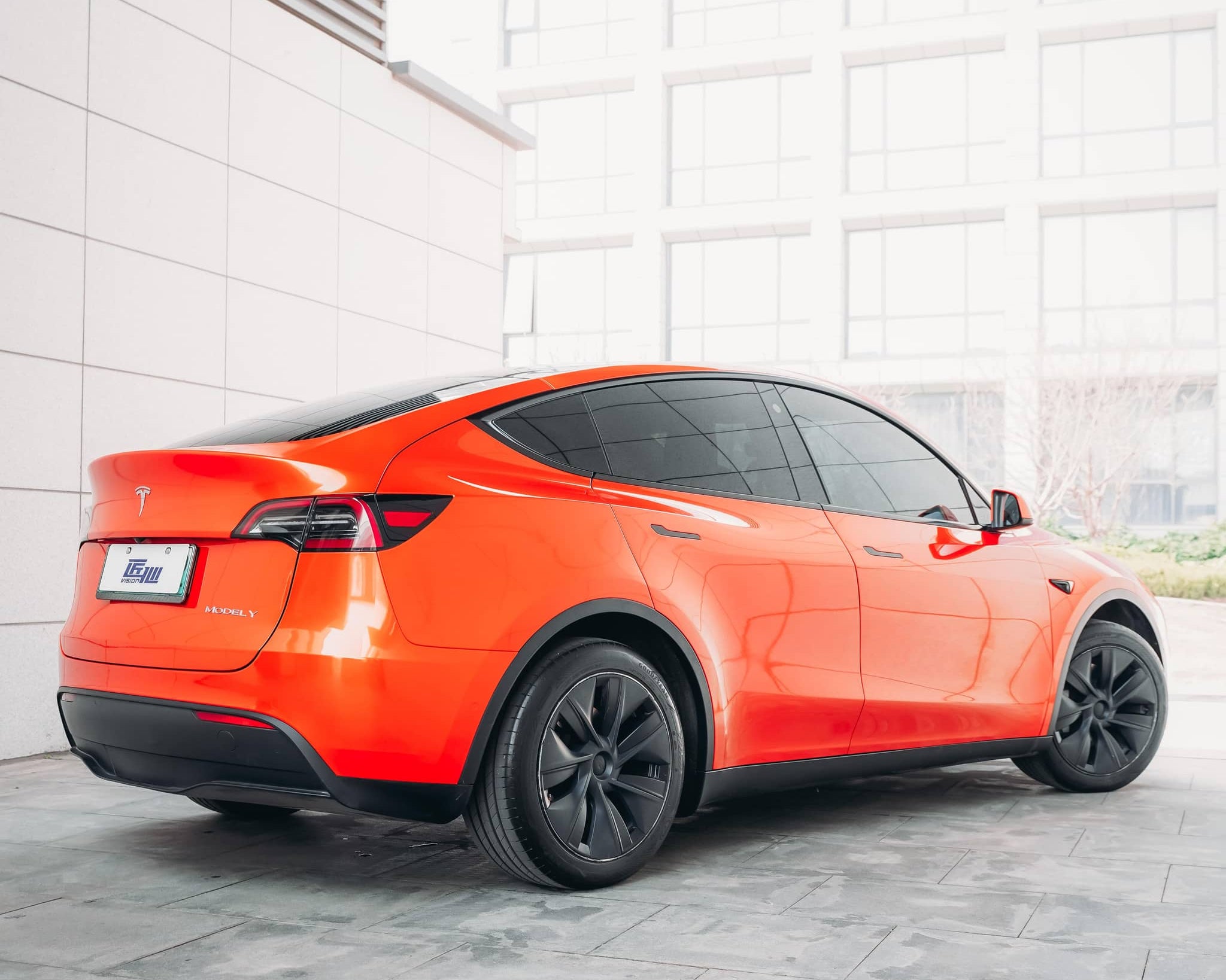 Orange Tesla Model Y wrapped using Pre-cut Tesla Wrap Kit by WrapBug with sleek black wheels and tinted windows