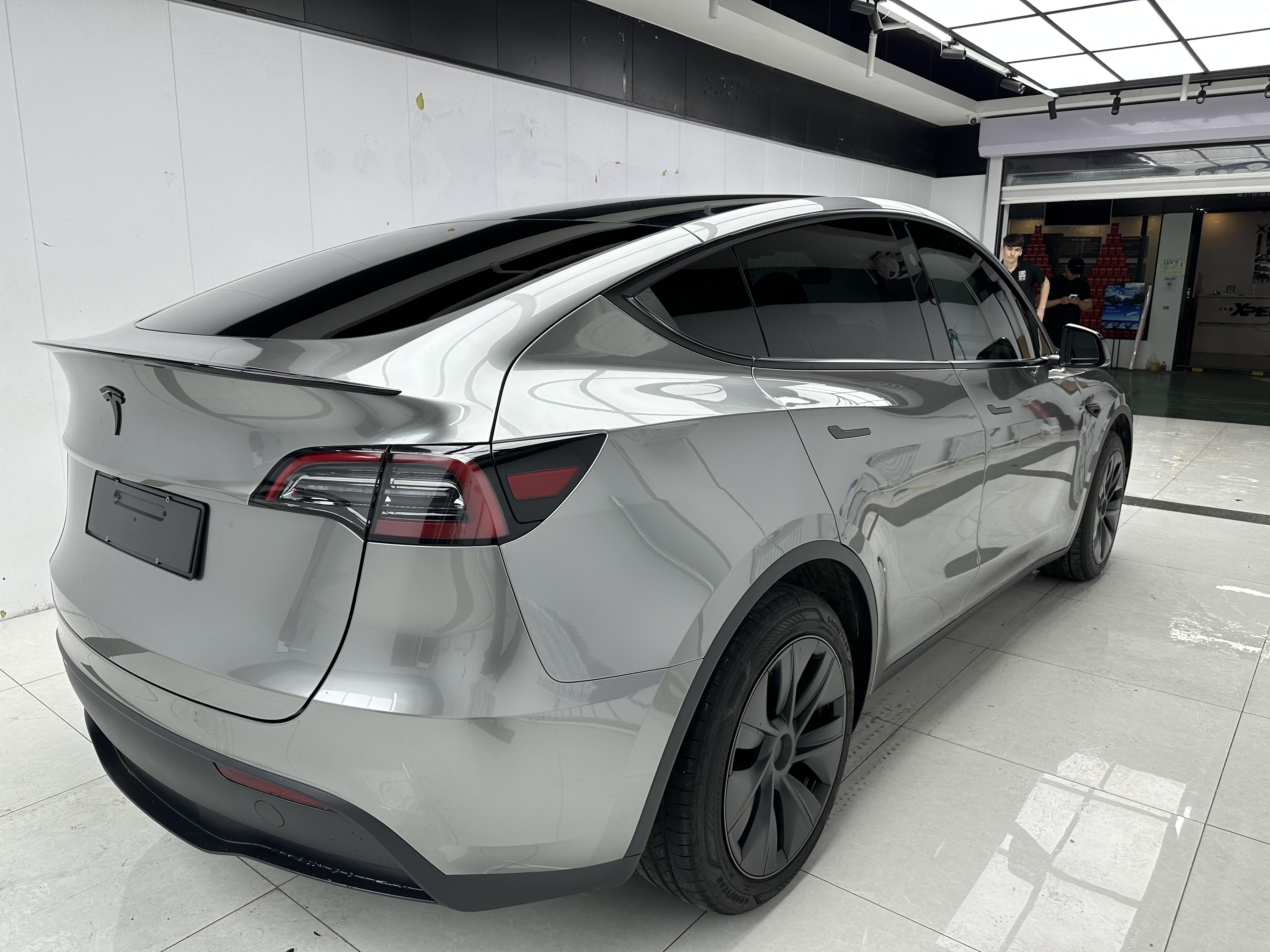 Silver Tesla Model Y featuring a glossy Pre-cut Tesla Wrap Kit from WrapBug in a clean garage