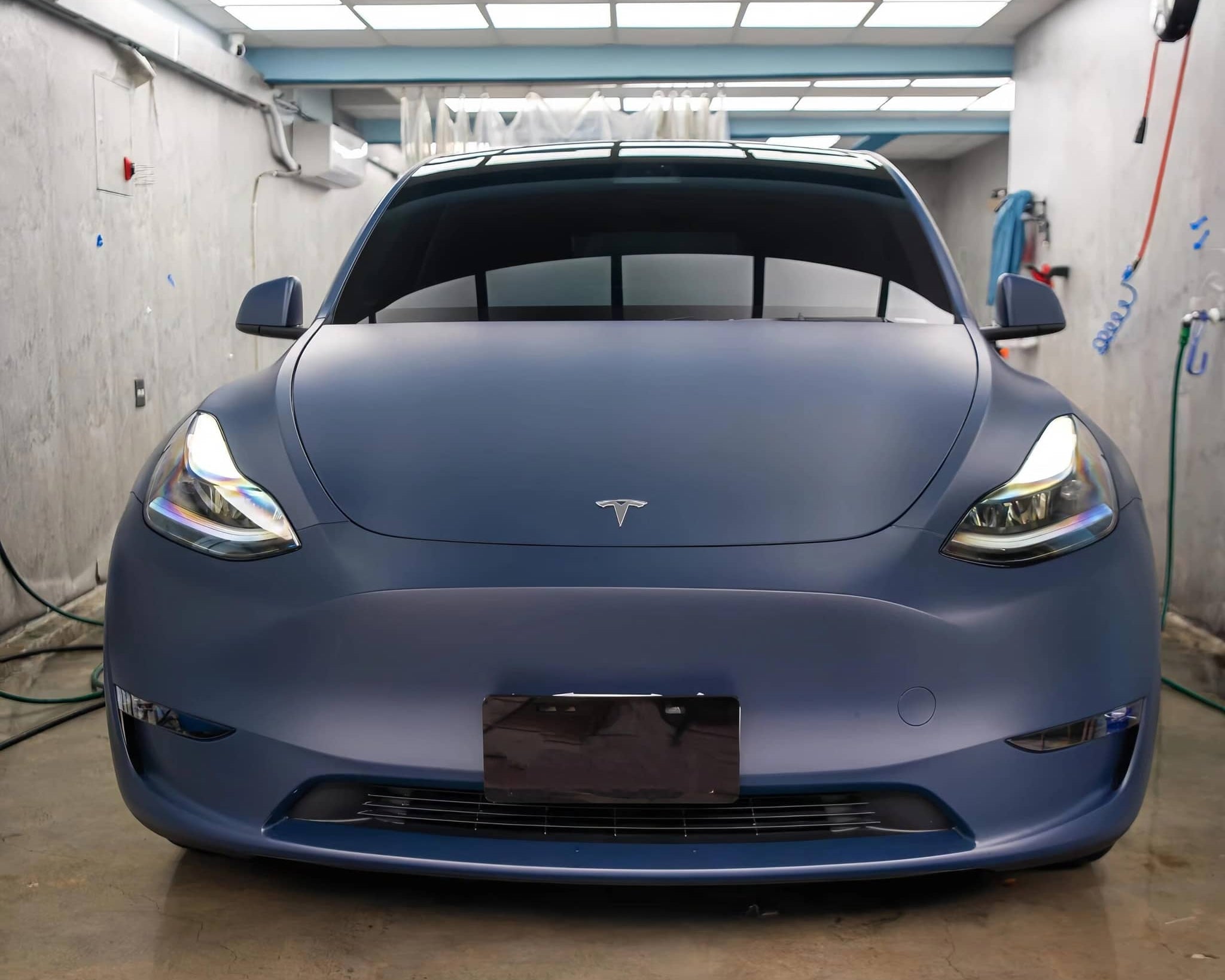 Matte blue tesla vinyl wrap on Tesla car in indoor garage by WrapBug