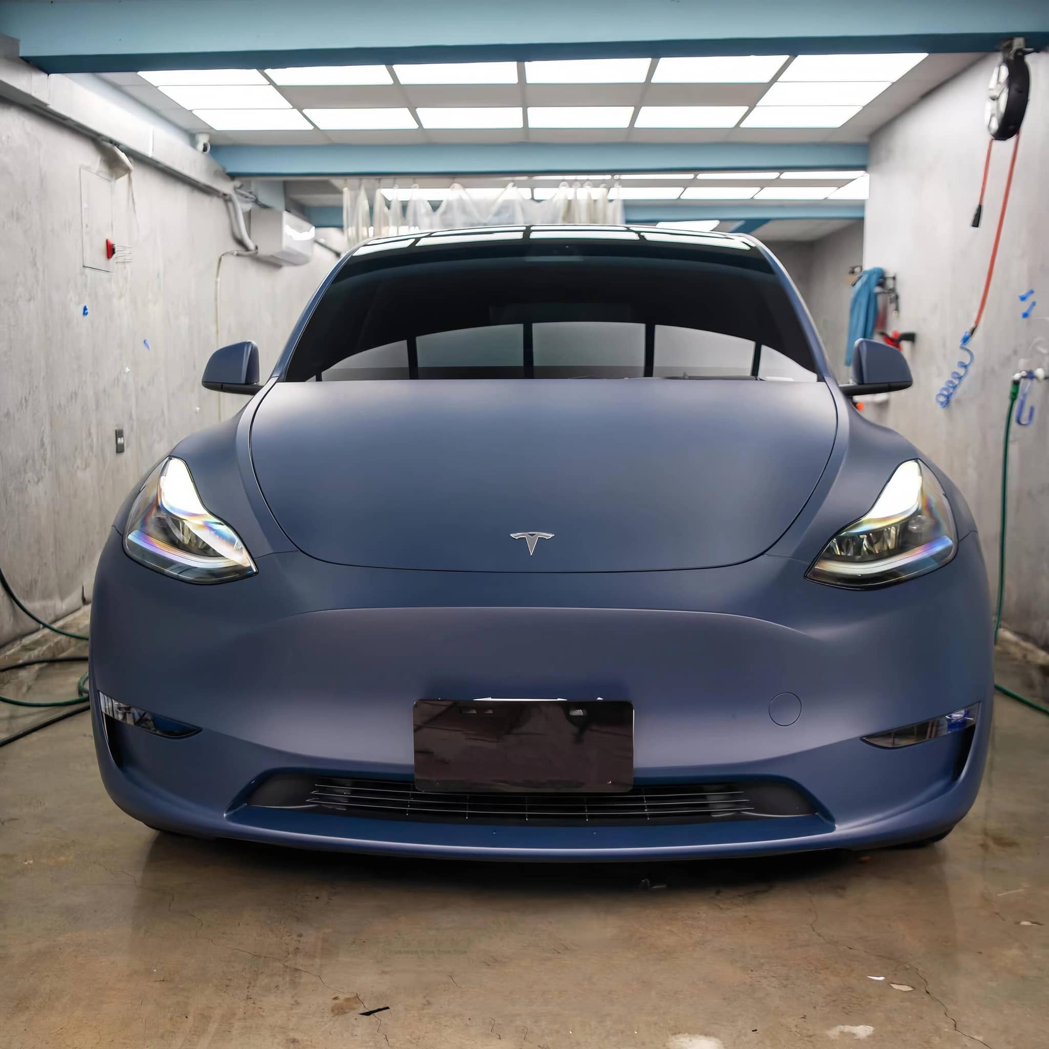 Matte blue tesla vinyl wrap on Tesla car in indoor garage by WrapBug