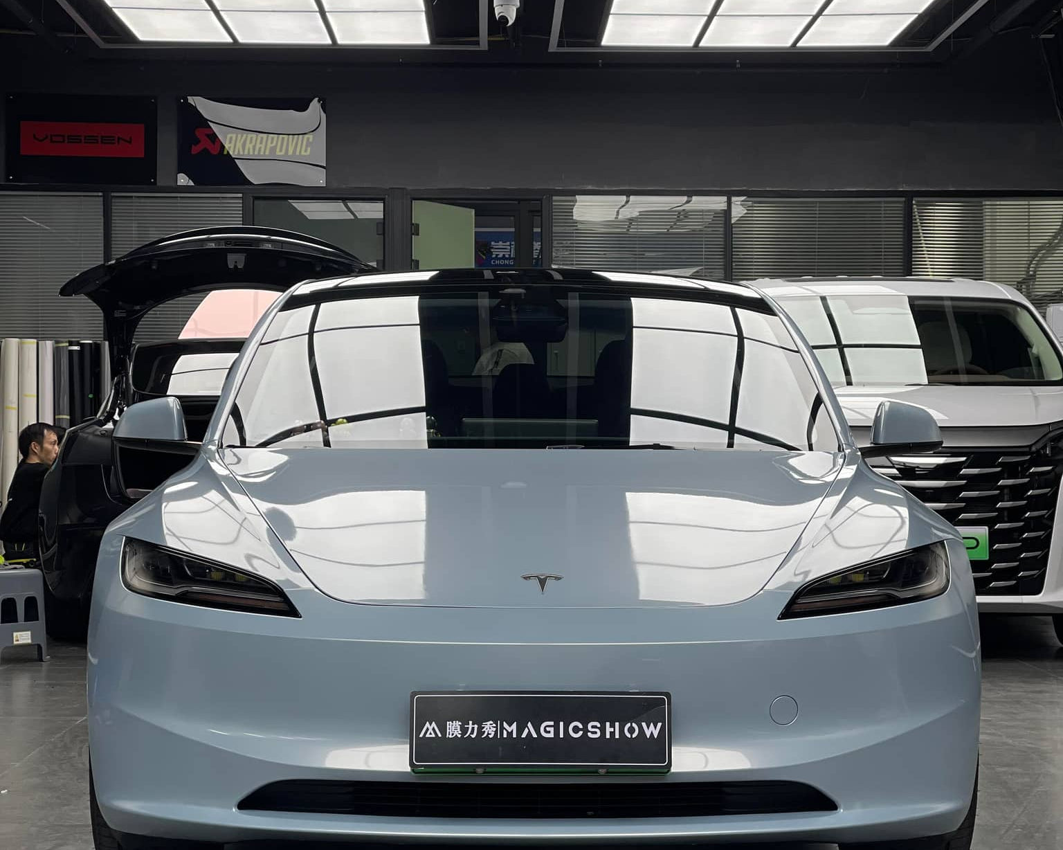 Front view of sleek silver Tesla Model X electric car with WrapBug branding in a showroom