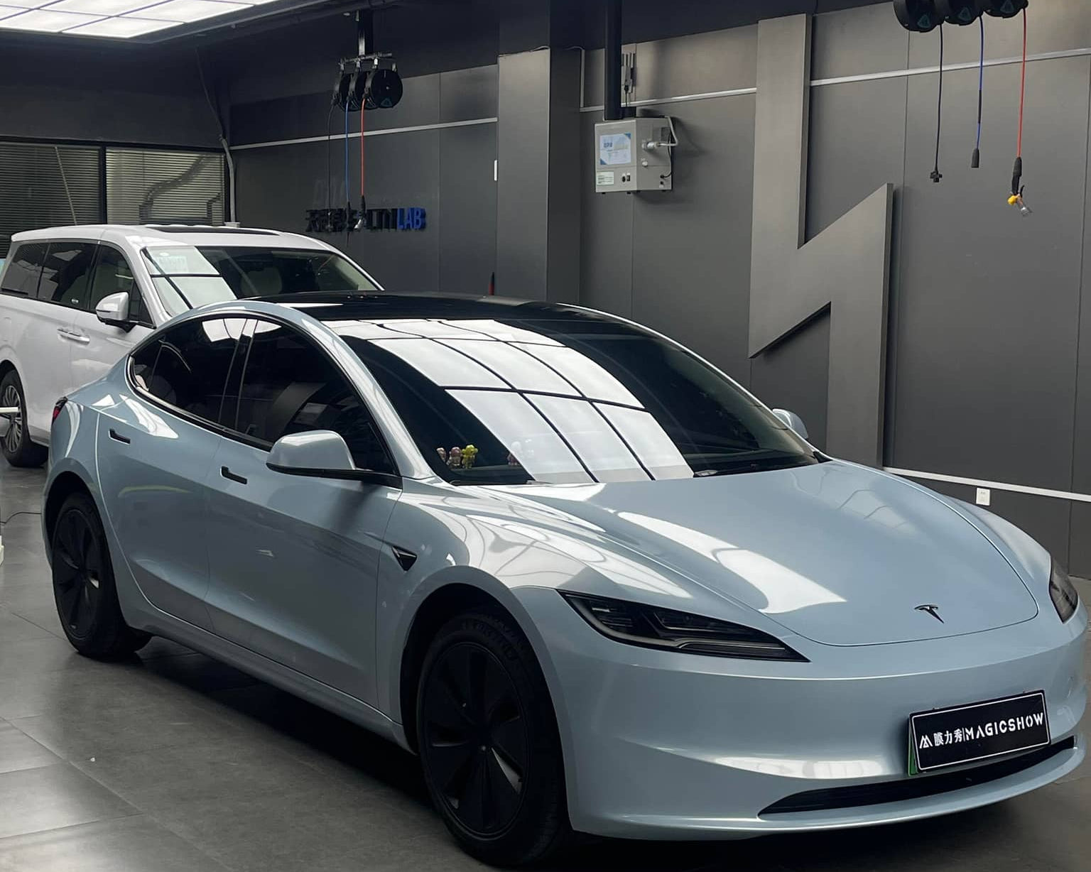 White Tesla Model S parked indoors with glossy finish under bright ceiling lights