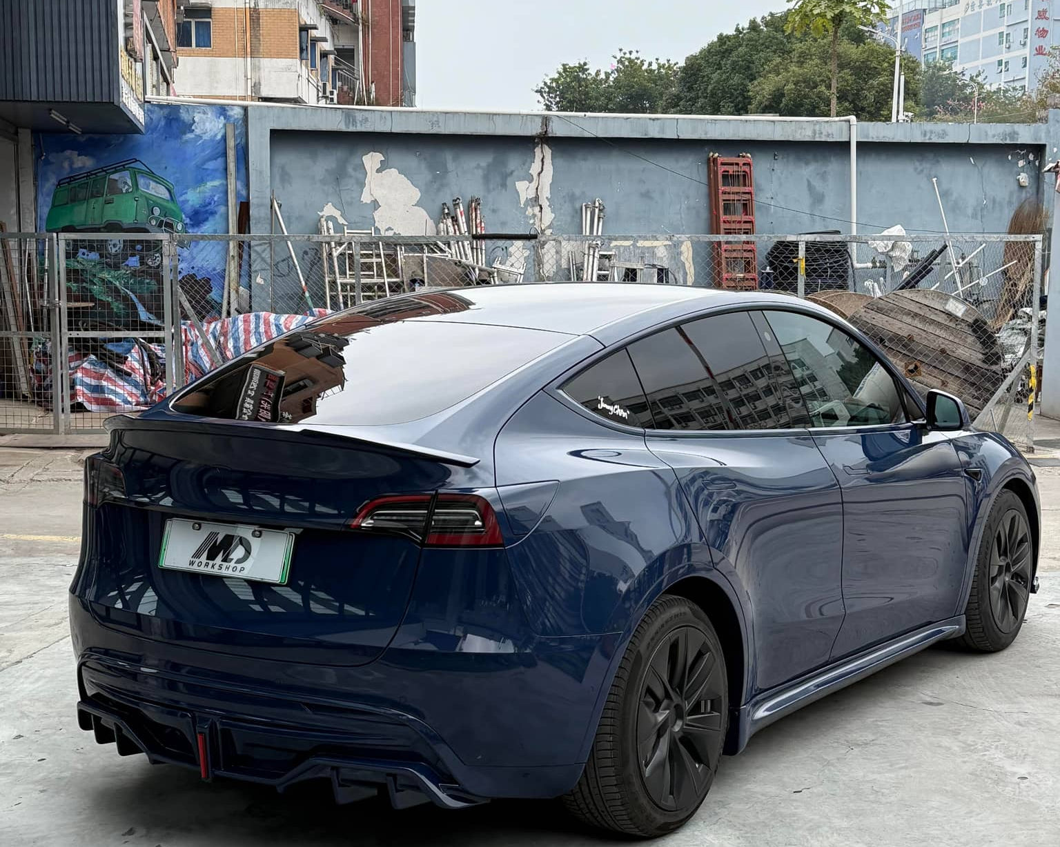 Dark blue Tesla Model Y with glossy finish using WrapBug Pre-cut Tesla Vinyl Wrap Kit parked in urban area
