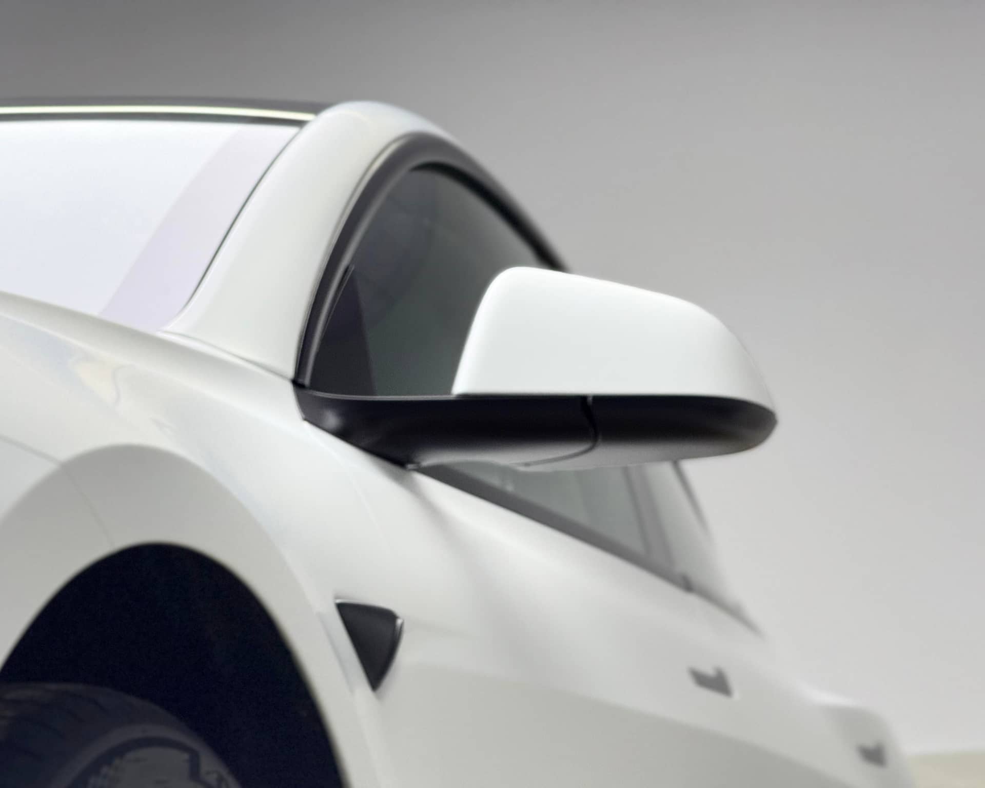 White Tesla side mirror and door panel wrapped using Pre-cut Tesla Vinyl Wrap Kit by WrapBug
