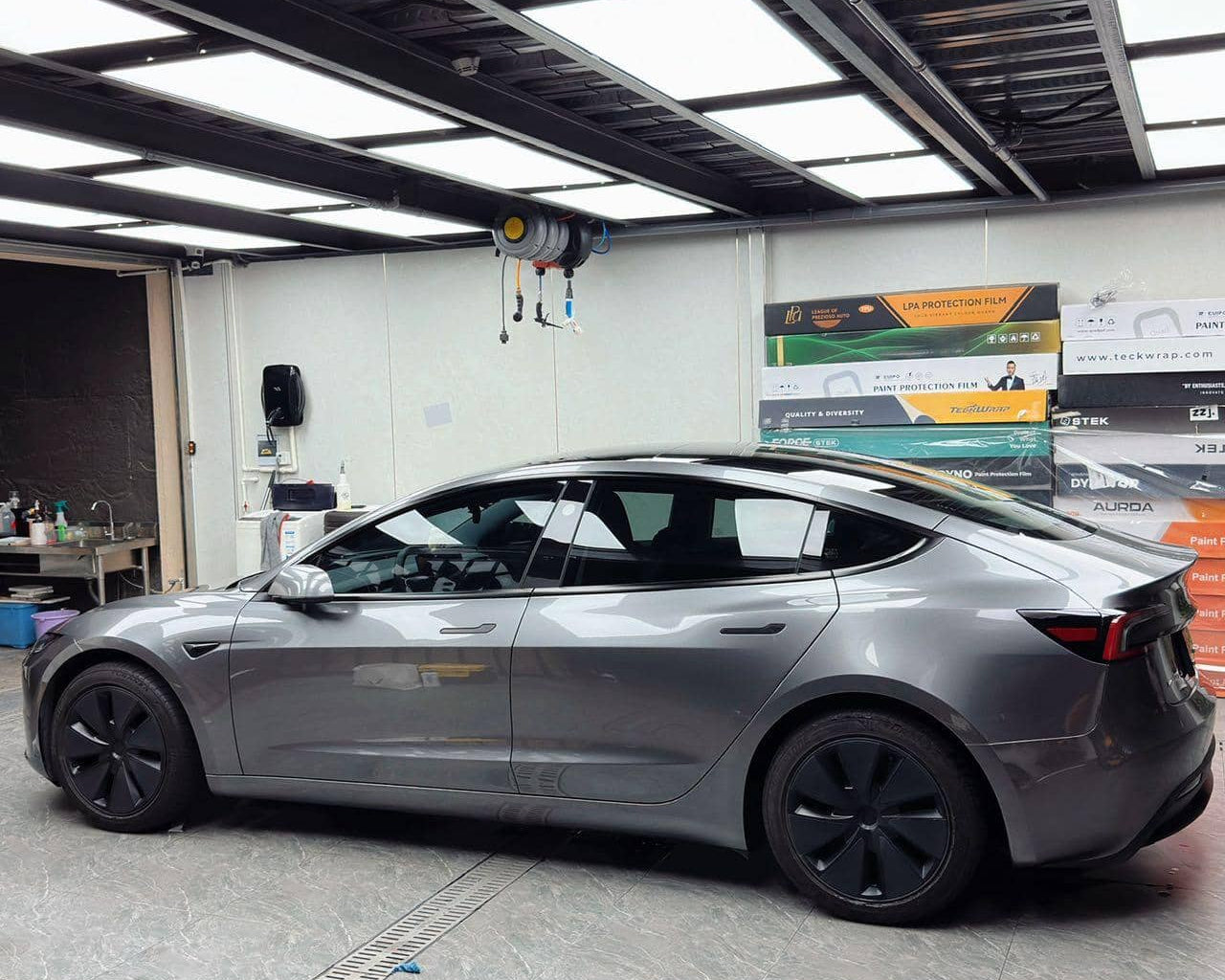 Tesla Model 3 in metallic gray wrapped with Pre-cut Tesla Vinyl Wrap Kit parked inside a garage