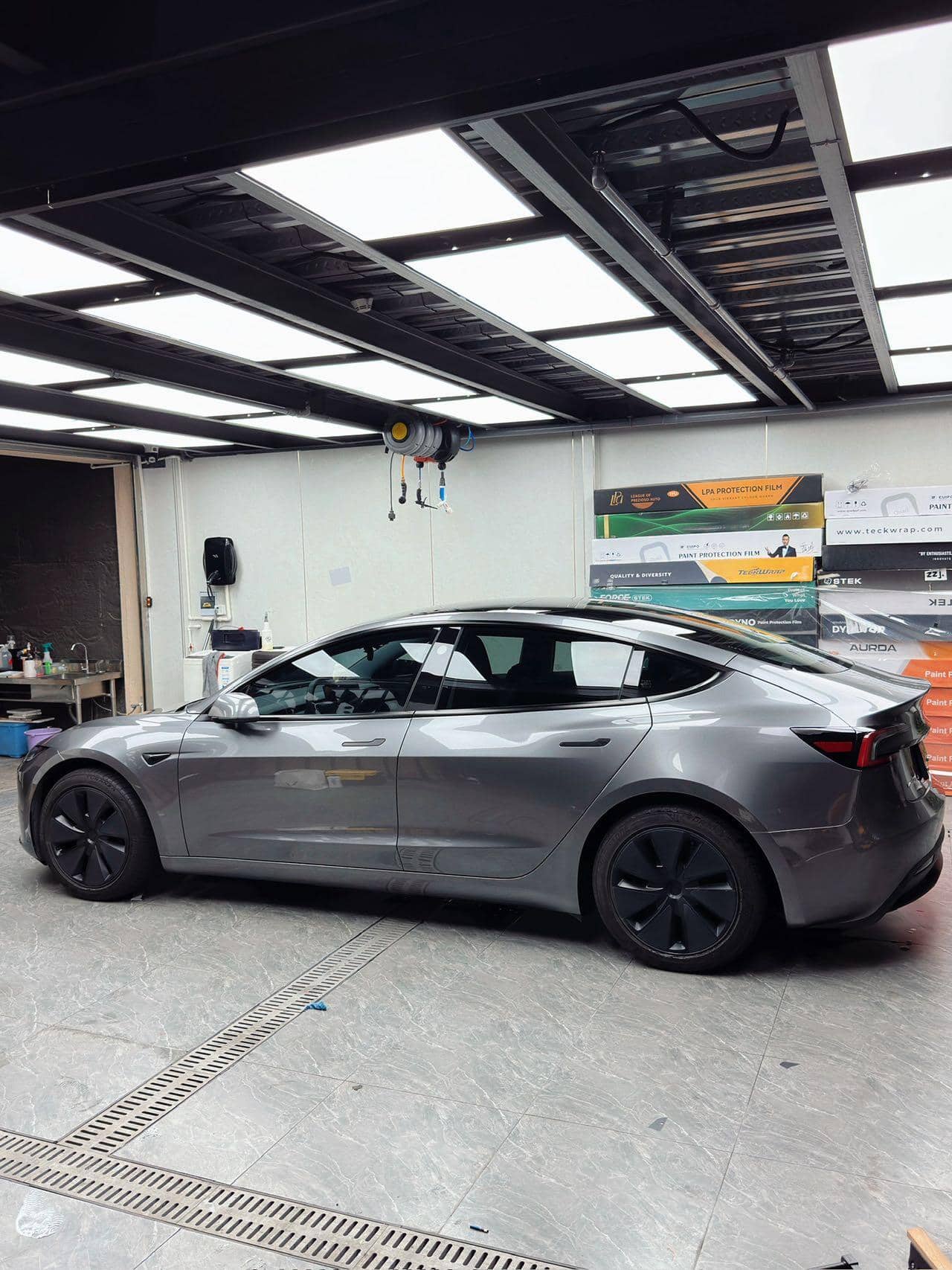 Tesla Model 3 in metallic gray wrapped with Pre-cut Tesla Vinyl Wrap Kit parked inside a garage