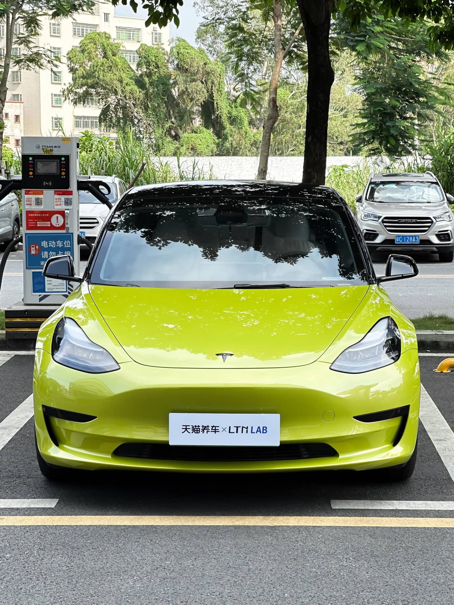 Pre-cut Tesla Vinyl Wrap Kit applied on bright green Tesla Model 3 front view in parking lot