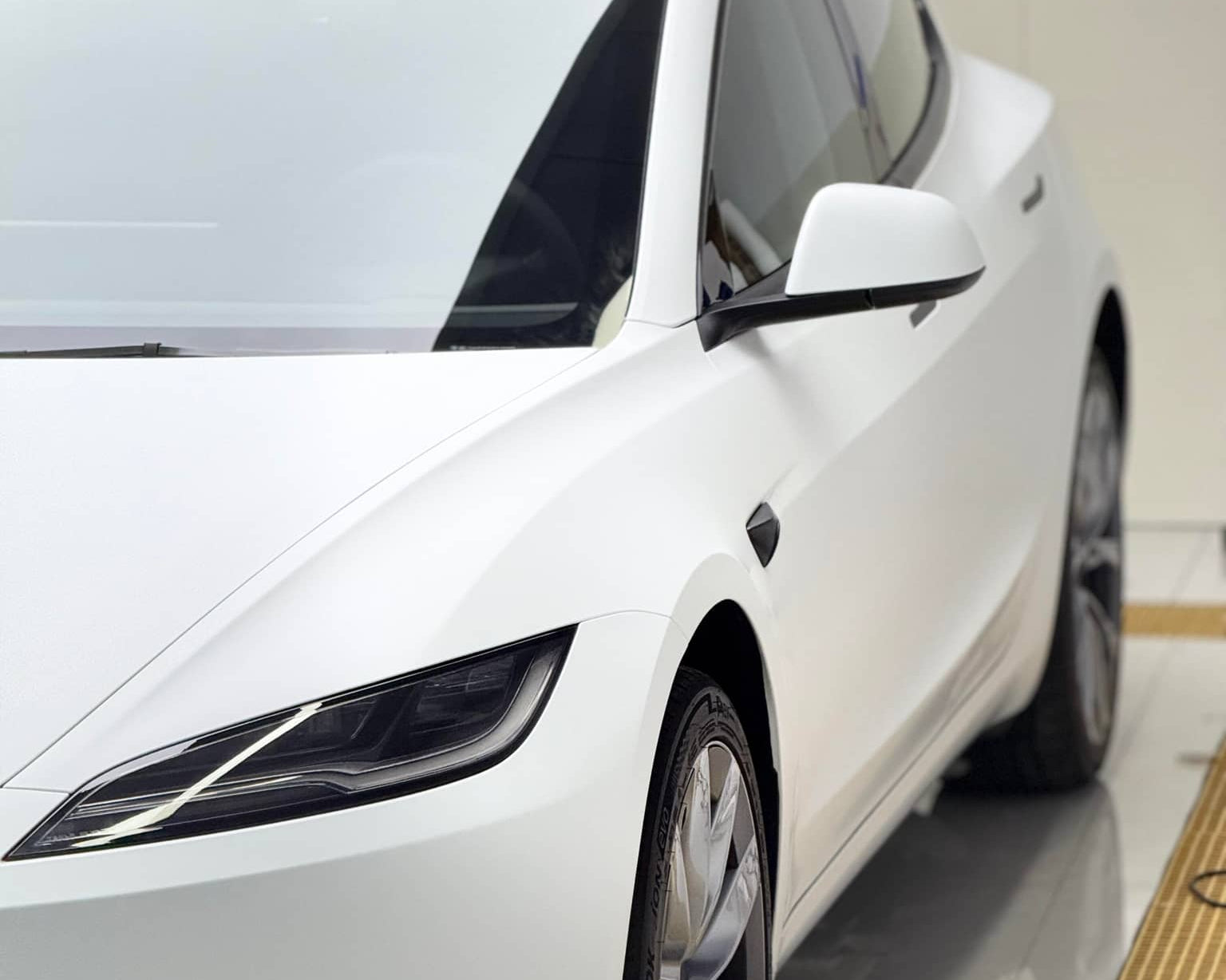 White Tesla Model 3 featuring Pre-cut Tesla Vinyl Wrap Kit by WrapBug on front side and wheel
