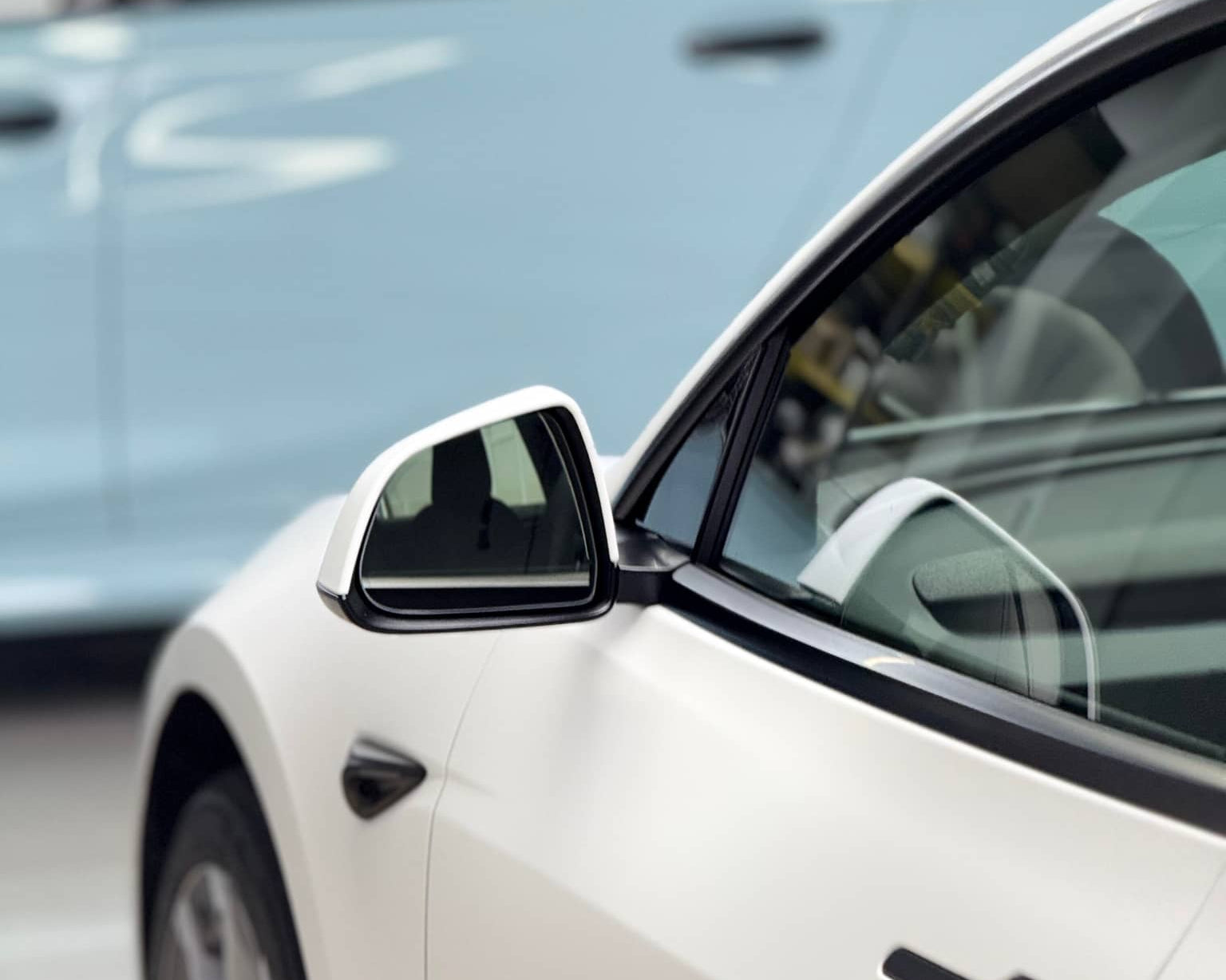 Close-up of white Tesla car showcasing the smooth finish of a Pre-cut Tesla Vinyl Wrap Kit by WrapBug