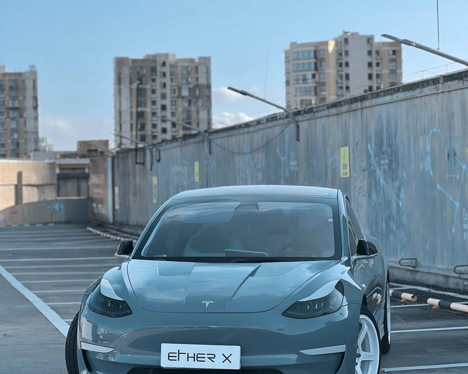 Tesla car parked in rooftop lot showcasing Pre-cut Tesla Vinyl Wrap Kit by WrapBug on front hood and body