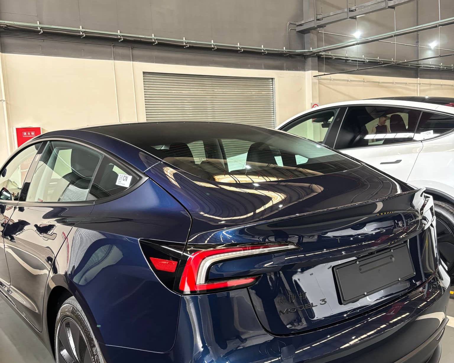 Blue Tesla Model 3 with a glossy finish showcasing the Pre-cut Tesla Wrap Kit by WrapBug in a garage