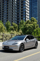 Silver Tesla Model 3 with black wheels parked on city street featuring WrapBug Pre-cut Tesla Wrap Kit