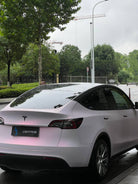 WrapBug matte pink Tesla Model Y parked outdoors with rain droplets on roof and tinted windows