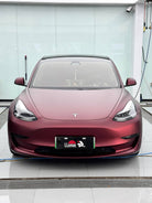 Front view of a matte maroon Tesla Model 3 electric car with sleek aerodynamic design